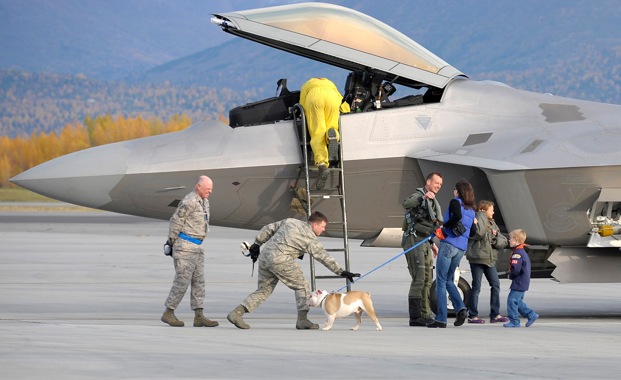 ELMENDORF AIR FORCE BASE, Alaska -- Lt. Col. Christopher Niemi greets his wife and the squadron mascot, Fado, after returning from a four-month deployment to Andersen Air Force Base, Guam. Niemi is an F-22 pilot and commander of the 525th Fighter Squadron here. (U.S. Air Force photo/Master Sgt Keith Brown)