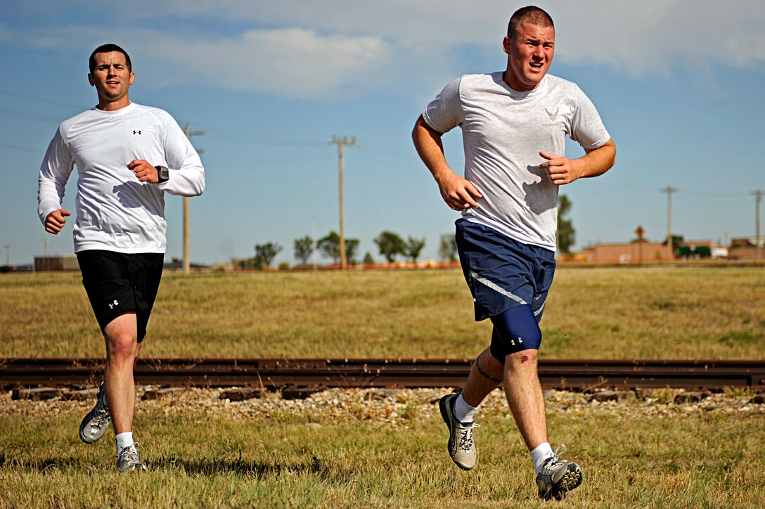 (Right) Airman 1st Class Steven Scalle, 28th Security Forces Squadron patrolman, and Staff Sgt. Patrick McMahon, 28 SFS patrolman, run during the Raider Challenge here, Sept. 25. The race featured eight different checkpoints throughout the base including Camp Lancer, the PRIDE hangar and Gateway Lake. (U.S. Air Force photo/Airman 1st Class Matthew Flynn)