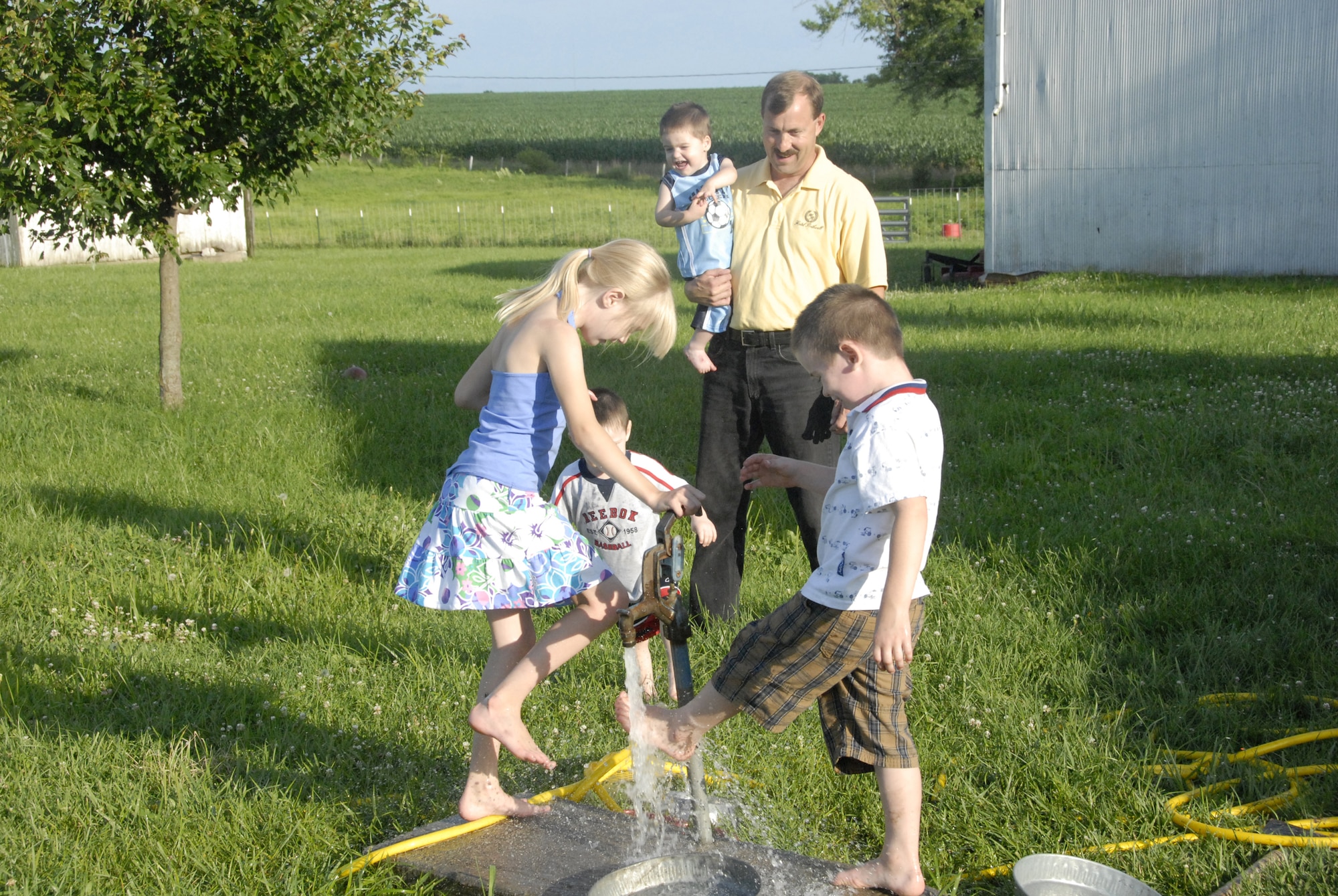 Tech. Sgt. Eric Anderson, 442nd Aircraft Maintenance Squadron, holds one of his foster children as he watches his daughter and his other foster sons enjoy playing in a water hydrant on a warm afternoon in their yard.  Sergeant Anderson, an A-10 crew chief, and his wife have been foster parents for several children in the past few years.  Sergeant Anderson is an Air Force reservist in the 442nd Fighter Wing, Whiteman Air Force Base, Mo. (U.S. Air Force photo/Senior Airman Danielle Wolf)