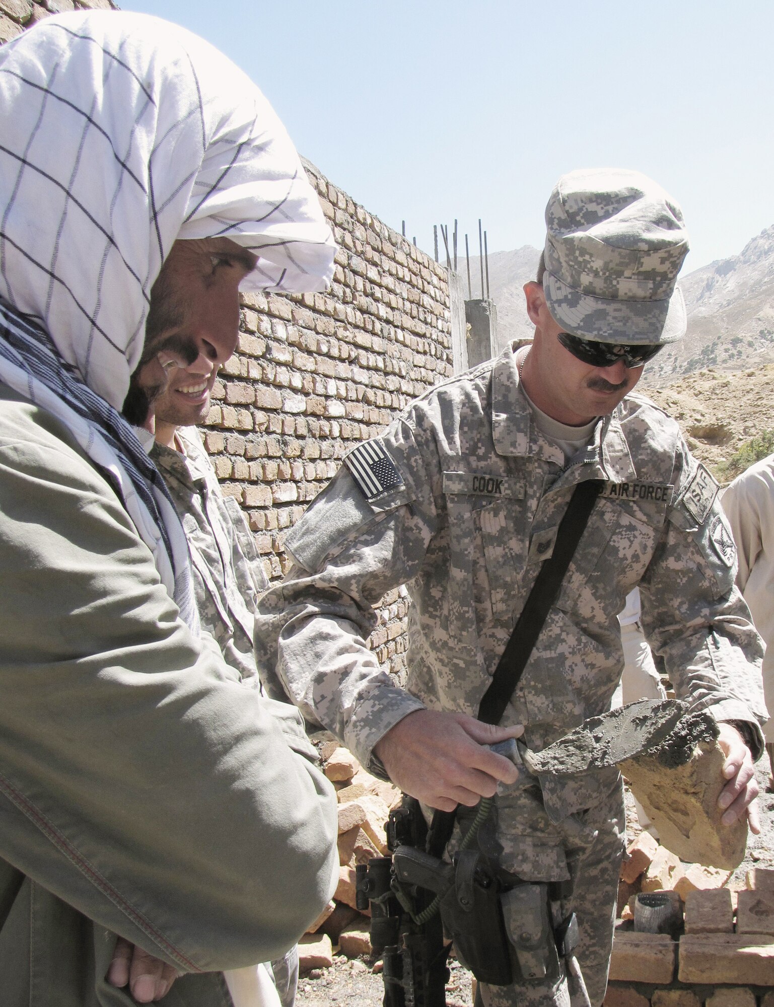 Tech. Sgt. Jonathan Cook shows Afghan construction workers how to apply cement to bricks evenly Sept. 6, 2009, in Panjshir, Afghanistan. Sergeant Cook is a civil engineer with the provincial reconstruction team here and is a Colorado native deployed from Nellis AFB, Nev. (U.S. Air Force photo/Staff Sgt. J.G. Buzanowski) 
