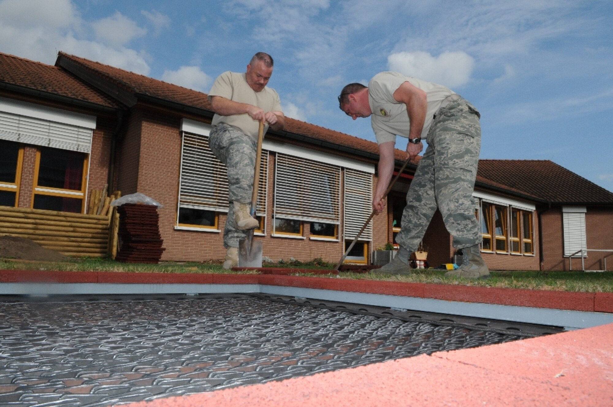 MISAU, Germany -- Master Sgt. Rich Rizzo (left) and Senior Master Sgt. Jim Downey install heavy foam padding around a newly implanted trampoline at the Haus Fur Kinder (Kindergarten) in the village, near Ramstein Air Base Sept. 24. The two members of 17th Air Force are among a group of Airmen from the unit working to restore the playground at the school. (USAF photo by Master Sgt. Jim Fisher)
