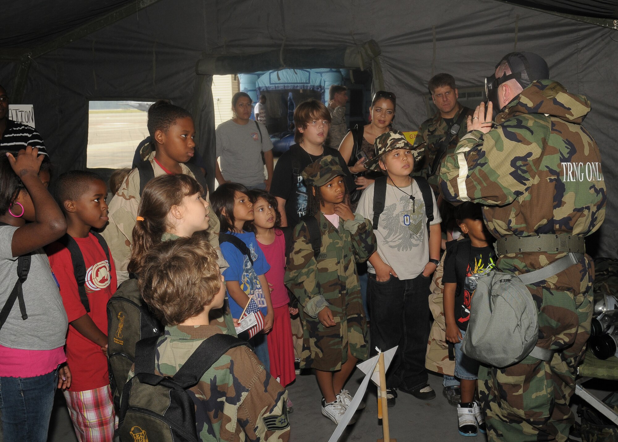 YOKOTA AIR BASE, Japan -- Tech. Sgt. Travis Kelsey, 374th Civil Engineer Squadron, shows children how to properly don a protective mask Sept. 26 during the base's Kids Understanding Deployment Operation Support event at Bldg. 400. K.U.D.O.S. is an annual event to help children better understand their parents' deployment by going through part of the process themselves. More than 275 children attended this year's event. (U.S. Air Force photo/Airman 1st Class Sean Martin)