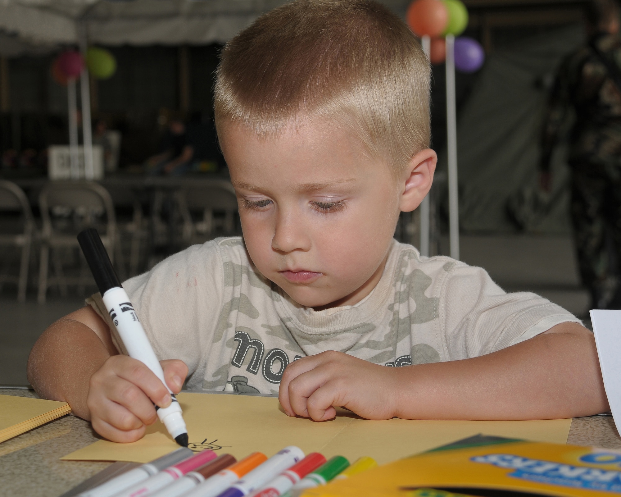 YOKOTA AIR BASE, Japan -- Kiefer Meuschke, son of Staff Sgt. Holli Meuschke, 374th Airlift Wing Chapel, writes a letter to troops downrange Sept. 26 during the base's Kids Understanding Deployment Operation Support event at Bldg. 400. K.U.D.O.S. is an annual event to help children better understand their parents' deployment by going through part of the process themselves. More than 150 children attended this year's event. (U.S. Air Force photo/Airman 1st Class Sean Martin)