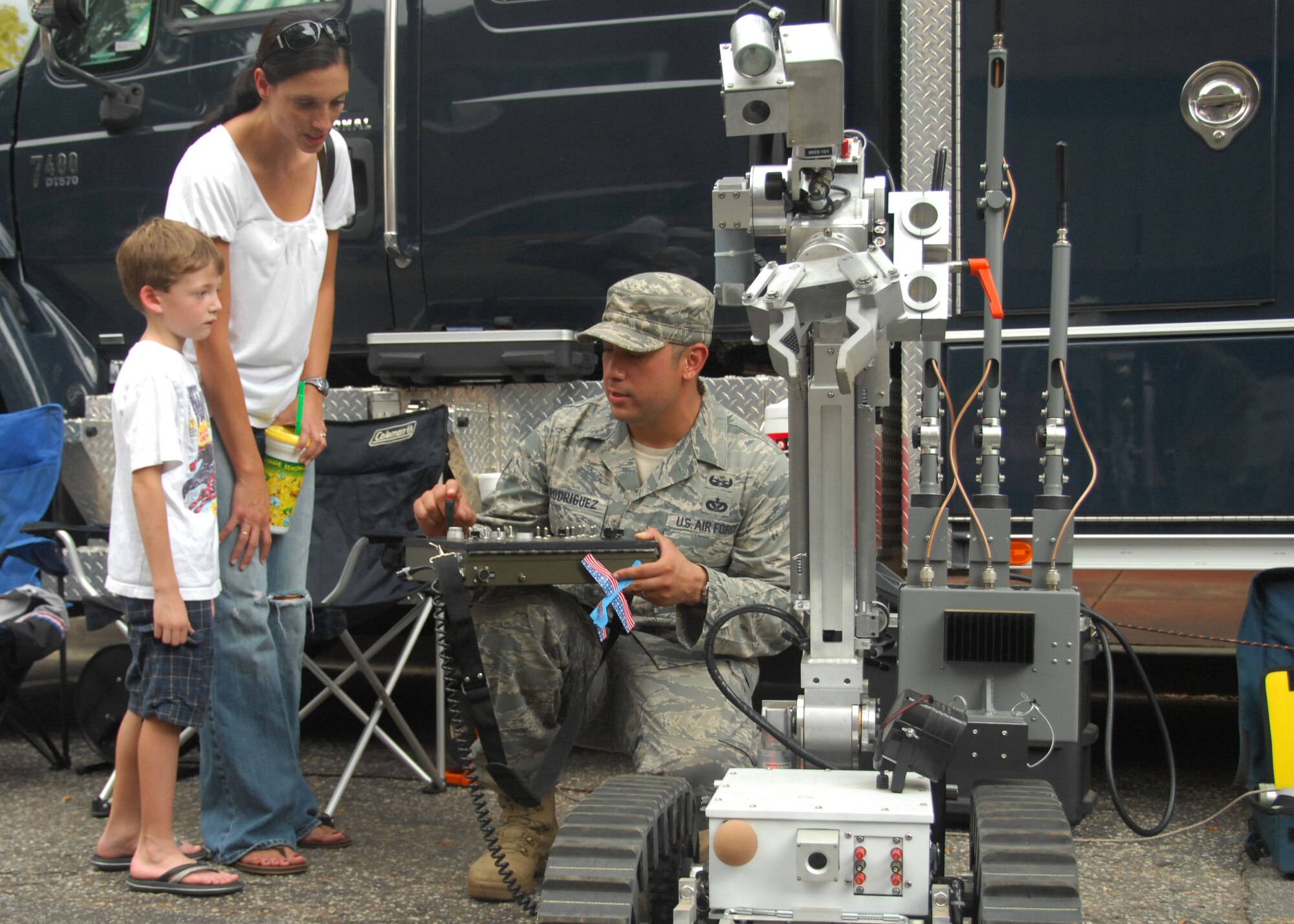 SHAW AIR FORCE BASE, S.C. -- Technical Sgt. Alejandro Rodriguez, 20th Civil Engineer Squadron explosive ordnance disposal, shows Bailey Wright, 6, and his mom Lisa Wright, how to control a robot used to pick up and examine explosives. The 20th CES was one of several units from Shaw Air Force Base that took part in the Sumter-Shaw Streetfest Sept. 25. (U.S. Air Force photo/2nd Lt. Emily Chilson)
