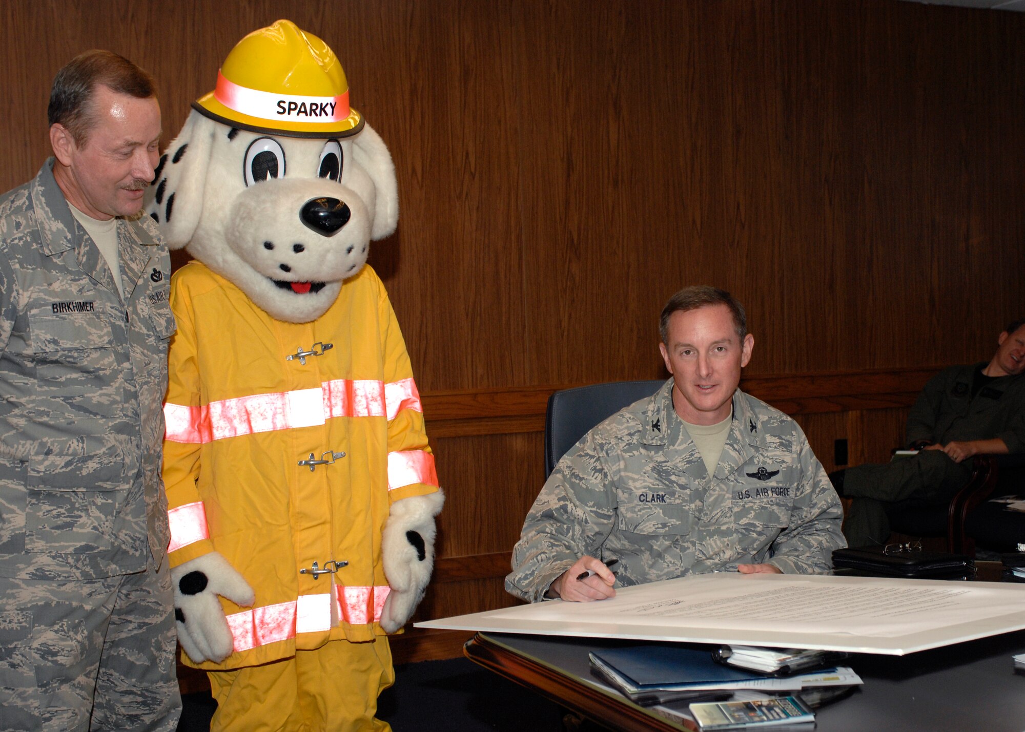 CANNON AIR FORCE BASE, N.M.-- Col. Stephen Clark, 27th Special Operations Wing commander, signs the proclamation for Fire Prevention Week, accompanied by Chief Master Sgt. Daniel Birkhimer, 27th Special Operations Civil Engineer Squadron, with Sparky the fire dog Sep. 29. Cannon's Fire Muster Fire Muster is Oct. 9 at Doc Stewart Park. Units wanting to participate in the festivities need to contact Mr. Ford at 575-784-2578.  (U.S. Air Force photo by Airman 1st Class James Bell)
