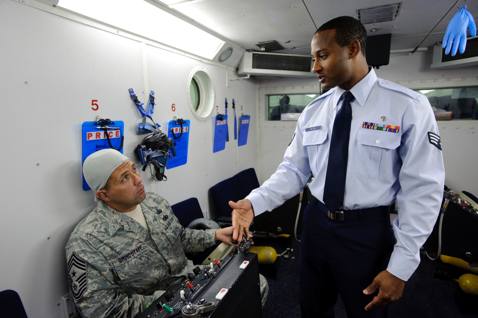 Chief Master Sgt. Max Grindstaff, 12th Flying Training Wing command chief from Randolph Air Force Base, Texas listens as Senior Airman Ivan Wilson, an aerospace physiology technician with the 12th Medical Group goes through the operational procedures of an oxygen regulator inside the bases high altitude chamber. (U.S. Air Force photo/Steve Thurow)