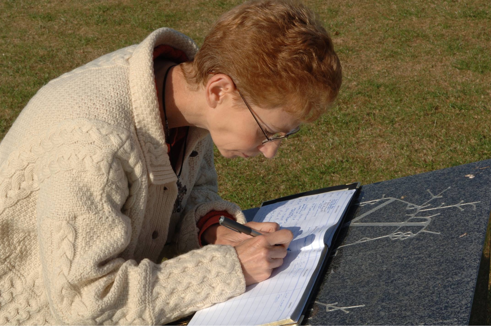 Ms. Louise Smedley-Hampson signs the guest book at the 303rd Bomb Group (Heavy) Memorial , RAF Molesworth, England.  She visited the base to commemorate the life and sacrifice of Staff Sgt. Joseph G. "Zip" Zsampar, U.S. Army Air Corps to whom her mother was engaged before his B-17 Flying Fortress "FDR's Potato Peeler Kids" was shot down in May 1943 with the loss of the whole ten-man crew. (U.S. Air Force Photo by Staff Sgt. Javier Cruz)