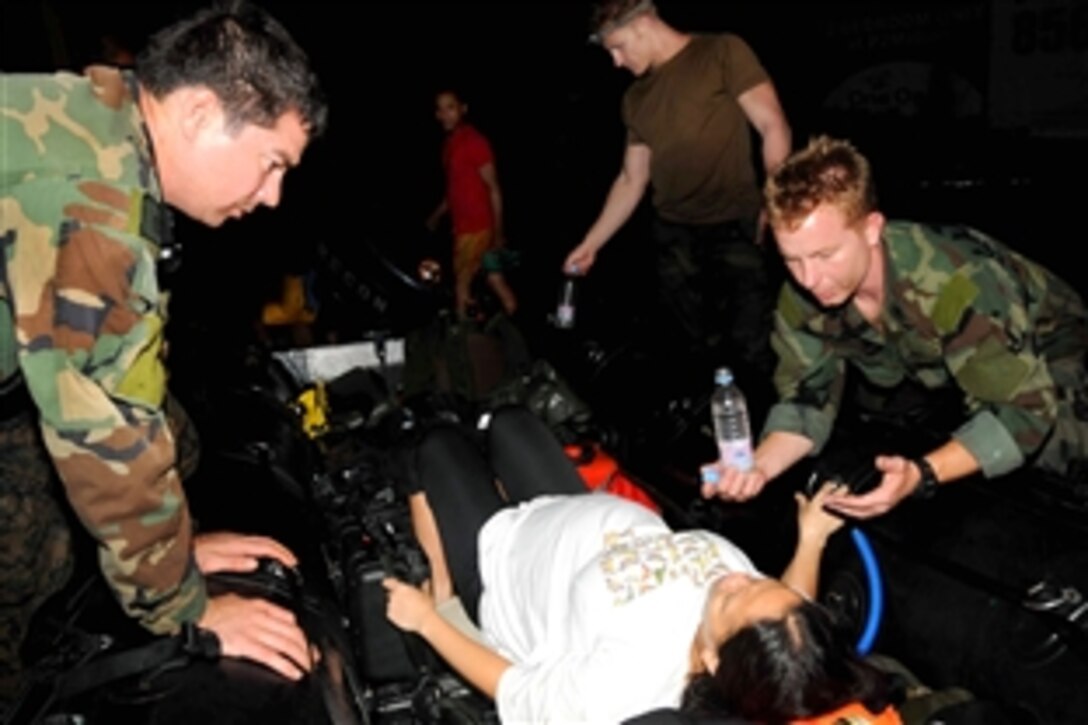 U.S. Navy medics assigned to Joint Special Operations Task Force-Philippines assist a woman in labor during relief efforts after flooding destroyed homes in Manila, Philippines, Sept. 27, 2009. The sailors delivered medical supplies, food, and rescued more than 52 people in Manila.