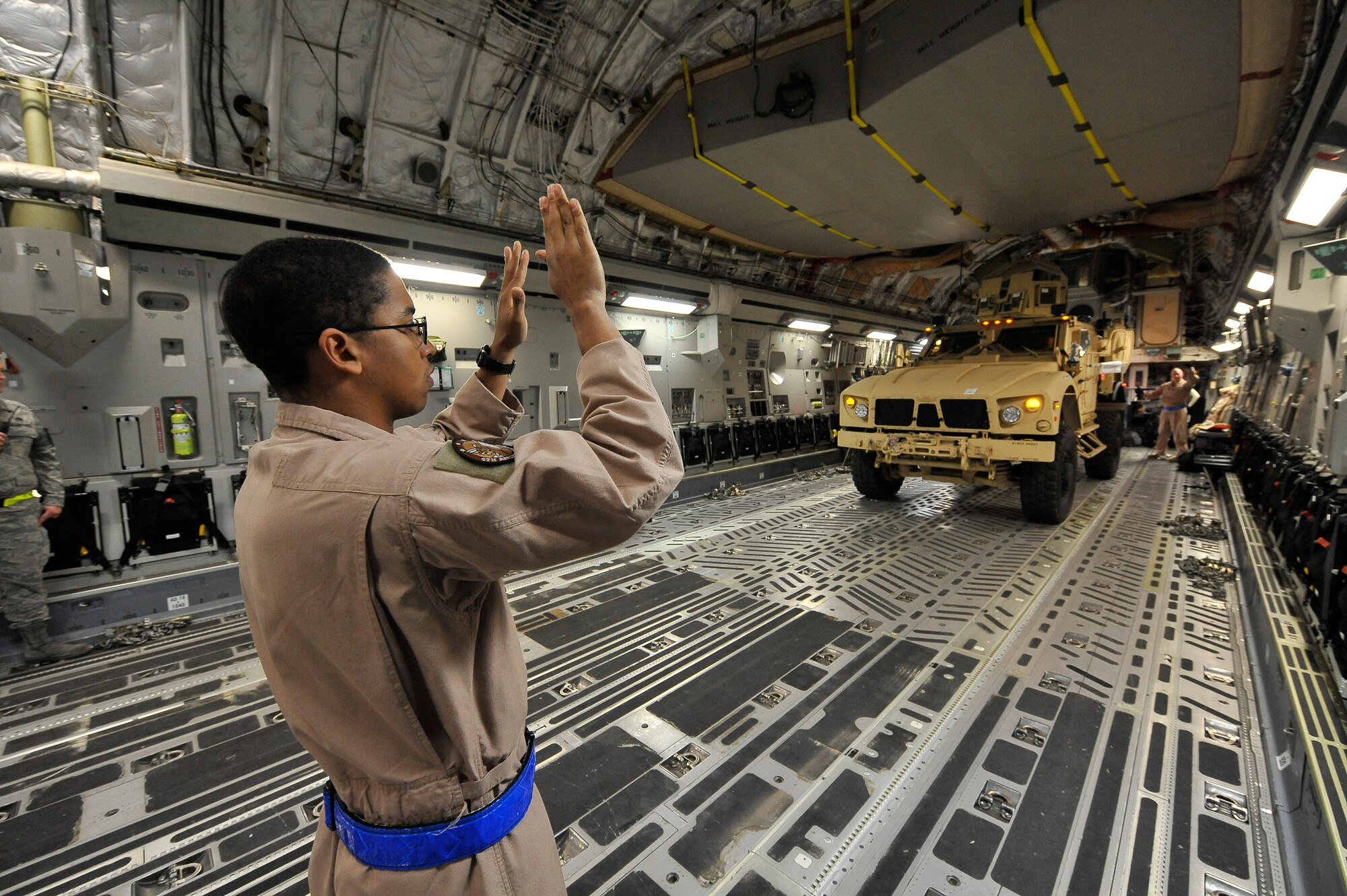 Senior Airman Robert Clark marshals one of two mine-resistant, ambush-protected all-terrain vehicles, or M-ATVs, onto a C-17 Globemaster III at Charleston Air Force Base, S.C., Sept. 30, 2009.  Airman Clark is a loadmaster with the 4th Airlift Squadron from McChord AFB, Wash.  The two M-ATVs are the first to be delivered to the Afghanistan theater for operational use. The C-17 is based out of McChord AFB. (U.S. Air Force photo/James M. Bowman)