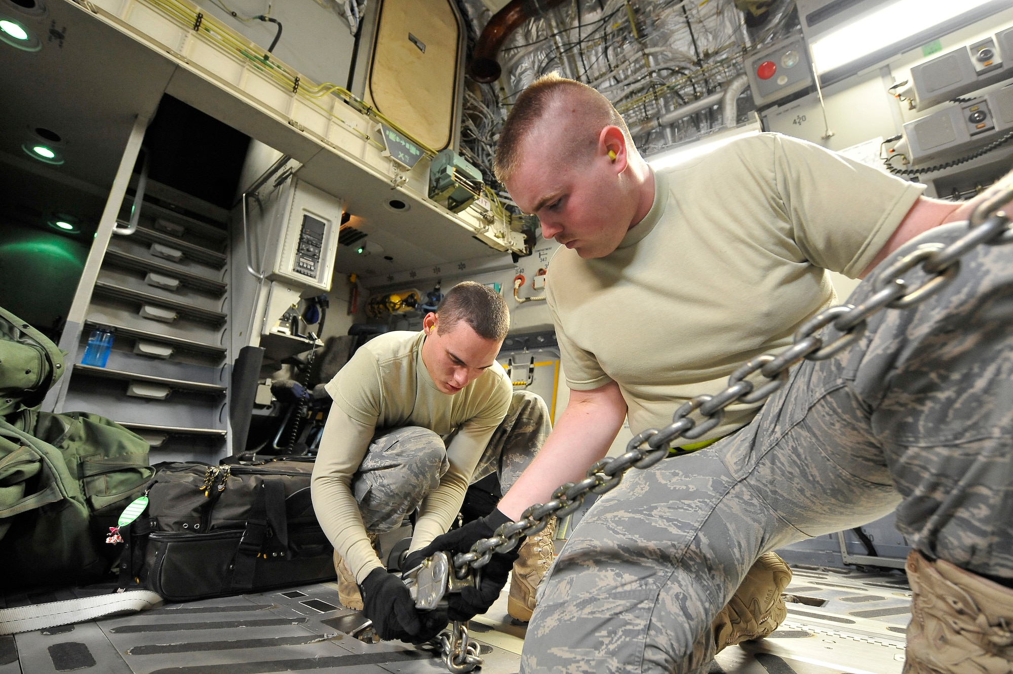 Airman 1st Class Daniel Anderson (left) and Staff Sgt. Charles Key use a tie down chain to secure one of two mine-resistant, ambush-protected all-terrain vehicles, or M-ATVs, in a C-17 Globemaster III at Charleston Air Force Base, S.C., Sept. 30, 2009.  The two M-ATVs are the first to be delivered to the Afghanistan theater for operational use. Both Airmen are air transportation specialists with the 437th Aerial Port Squadron at Charleston AFB. The C-17 is based out of McChord AFB, Wash. (U.S. Air Force photo/James M. Bowman)