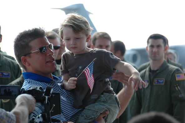 MCGUIRE AIR FORCE BASE, N.J. -- Maj. Tommy Marquardt holds his son, Jack, while the Military Channel films the major's recent surprise greeting by his fellow Air Force Reserve wing members.The C-17 pilot is being featured in a documentary entitled "The Return Salute" set to air Nov. 11 at 10 p.m. The documentary captures the pilot's story of recovering from Deep Vein Thrombosis, a condition where a blood clot formed within his leg resulting in him losing part of his limb. Major Marquardt's goal is to fly again. (U.S. Air Force photo/Master Sgt. Donna T. Jeffries) 


