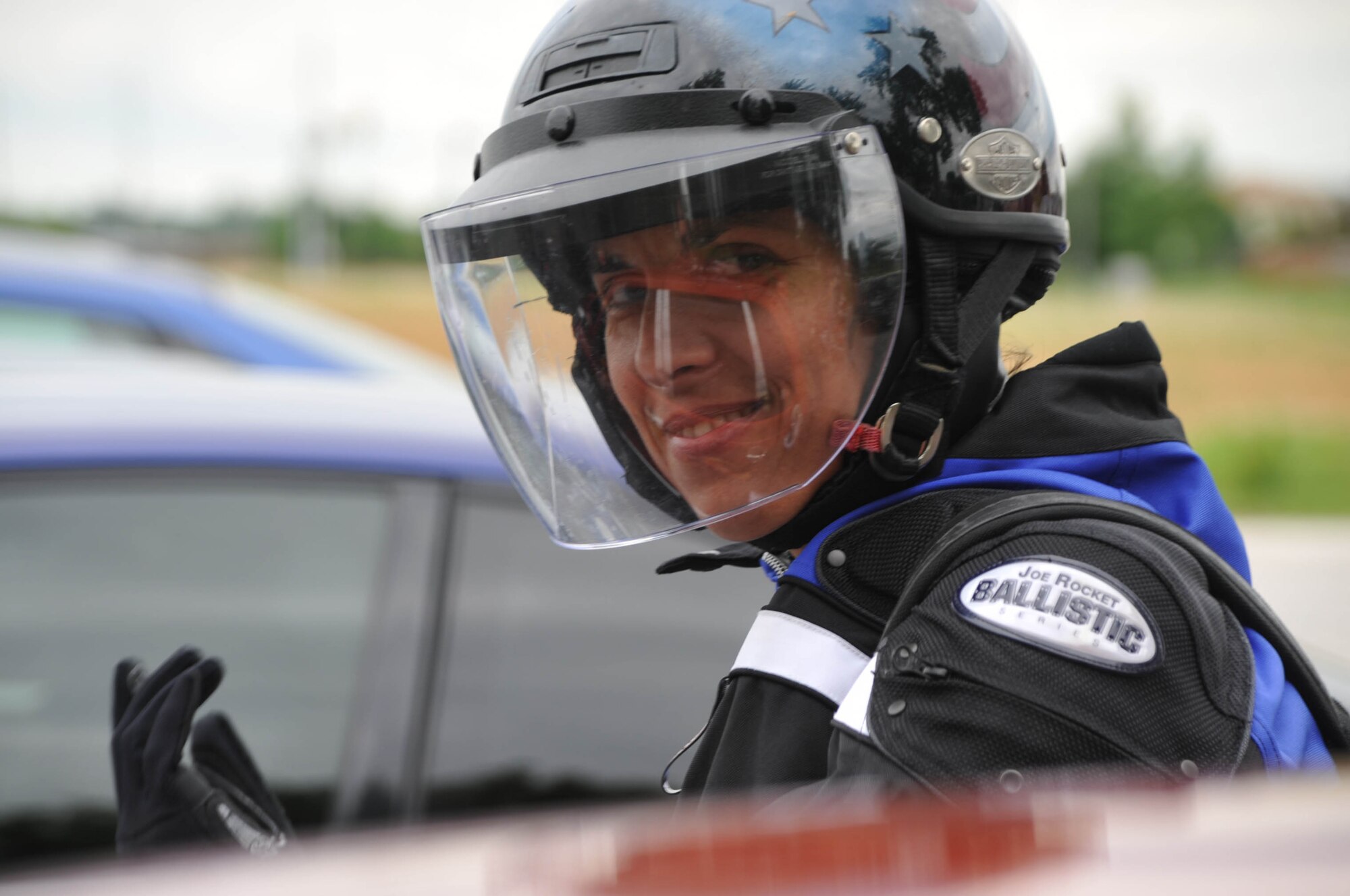 Command Chief Master Sgt. Sandra Santos puts on her riding gloves, protective jacket with pads, and patriotic helmet before hitting the open highway.  She helped kick off a Top Three Bike Run event to raise money and awareness of enlisted programs.  (U.S. Air Force photo/Maj. Stan Paregien)