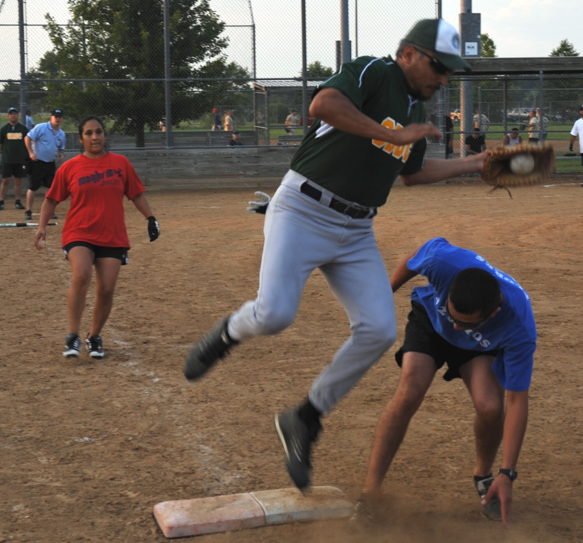 Senior Master Sergeant Teri Ray (in red) watches as a member of her 932nd Airlift Wing softball team makes it safely back to first base during a recent game at Scott Air Force Base.  The softball games are good for stress relief and accomplishing a fun goal together alongside people from throughout the unit that members may not normally work with.  (U.S. Air Force photo/Maj. Stan Paregien)