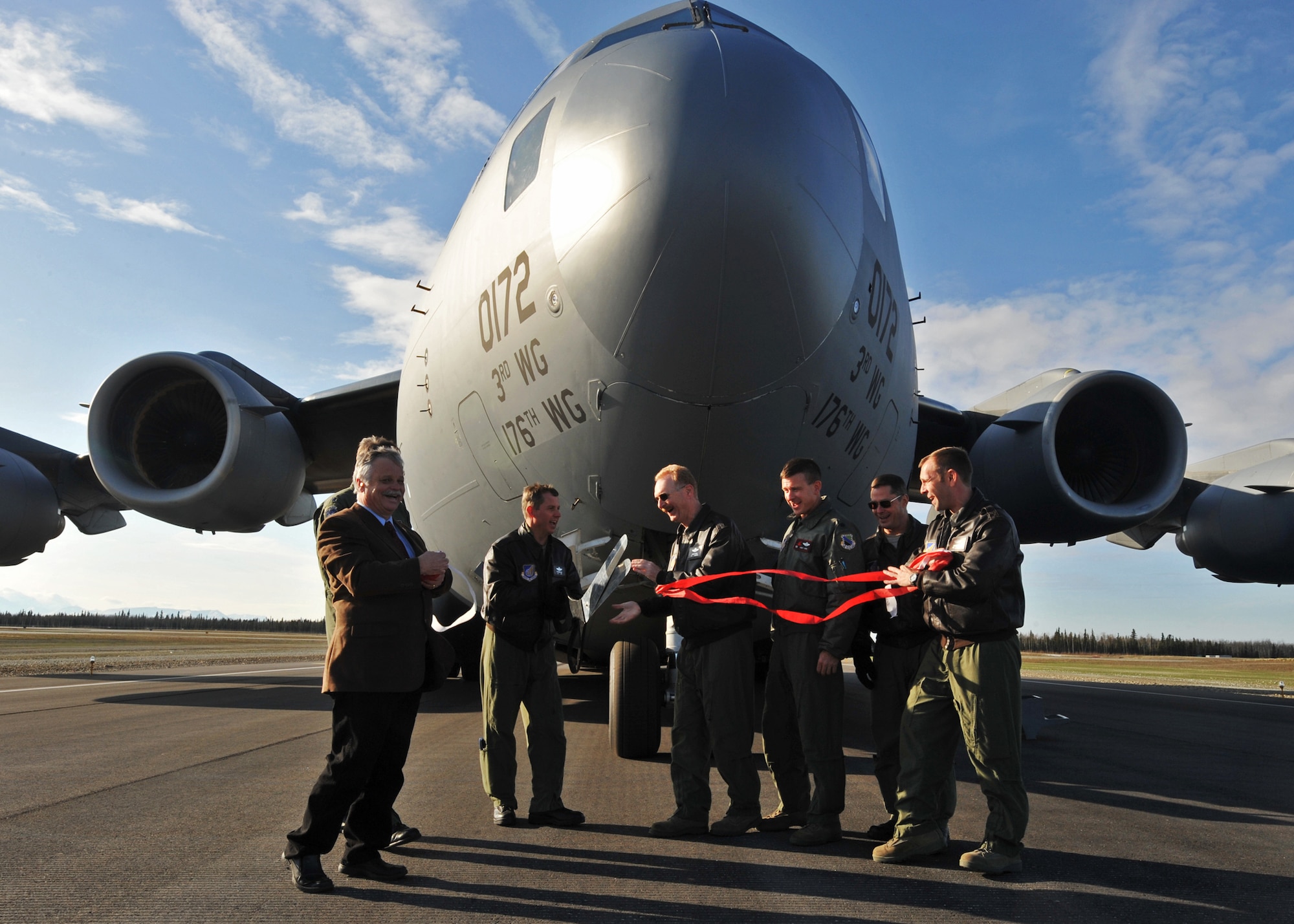 ALLEN ARMY AIRFIELD, Alaska -- Brig. Gen. Charles Foster, 176th Wing Commander, and Col. Thomas Bergeson, 3rd Wing Commander, cut a ribbon celebrating a newly opened runway on Allen Army Airfield Sept. 29, 2009. A C-17 Globemaster III stands in the background after performing an assault landing for the audience gathered during the ceremony. (U.S. Air Force photo/Senior Airman Laura Turner)