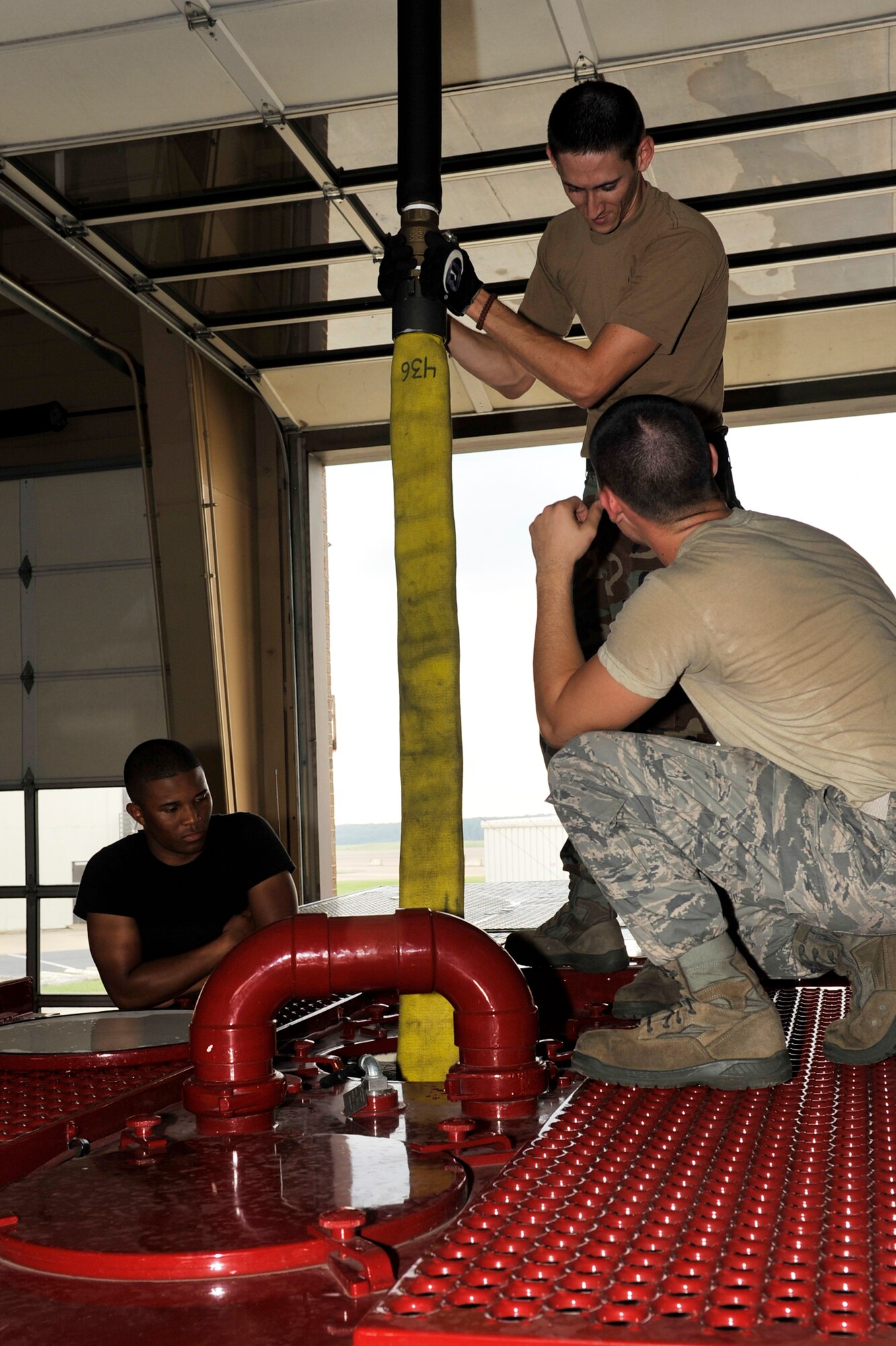 From left, Airman Curtis Sinkfield, Staff Sgt. Robert Starkey, and Airman Daniel O'Conner, 19th Civil Engineering Squadron fire fighters, use an overhead water fill to refill a fire truck on base Sept 21. The P19 crash truck can hold up to 1,000 gallons of water. (U.S. Air Force photo by Airman 1st Class Lausanne Pacheco)