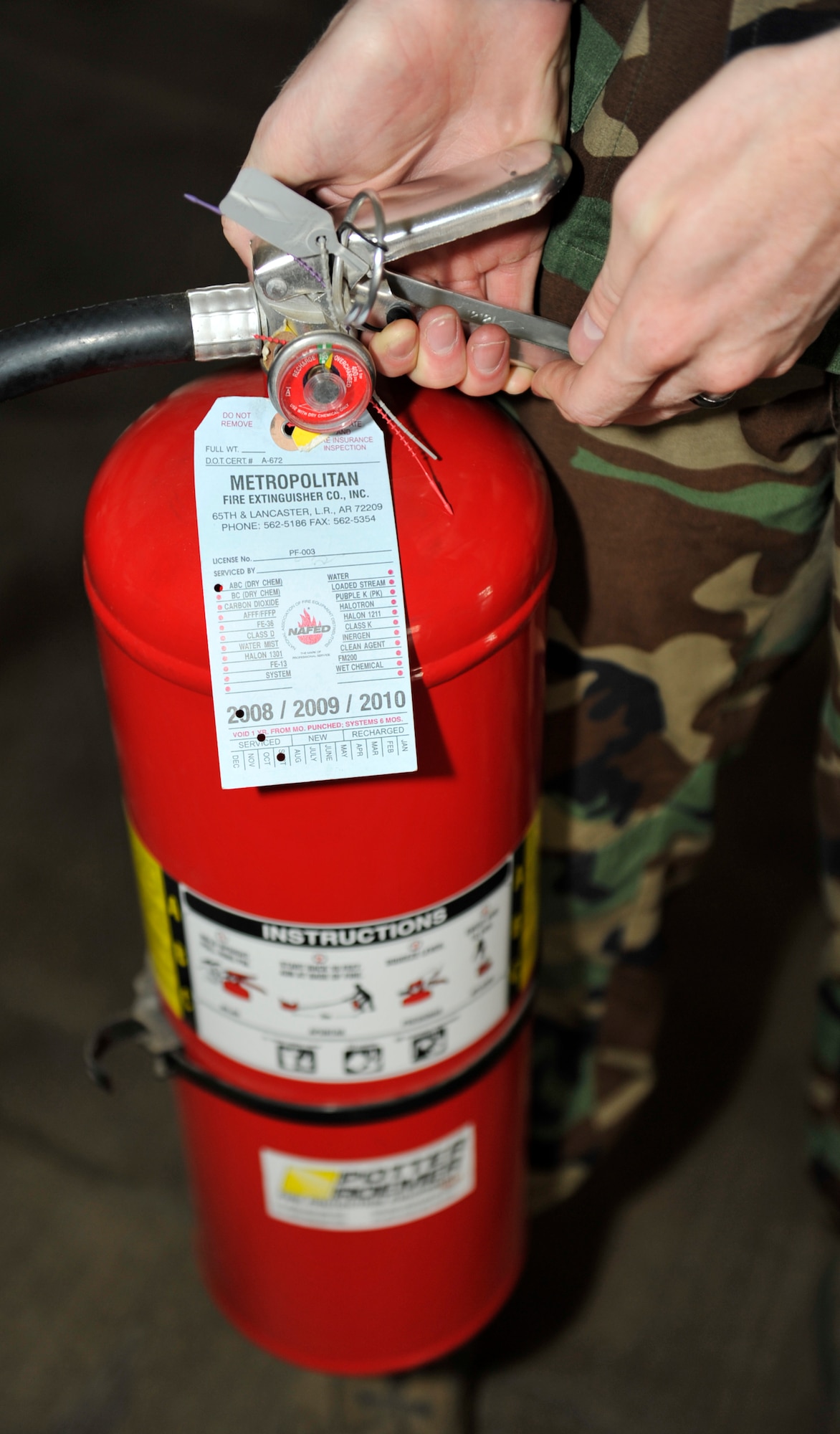Airman 1st Class Andrew Sloan, 19th Civil Engineering Squadron fire fighter, inspects a fire extinguisher Sept 21. A simple and easy way to remember how to operate a fire extinguisher is "P.A.S.S." - pull, aim, squeeze and sweep. (U.S. Air Force photo by Airman 1st Class Lausanne Pacheco)