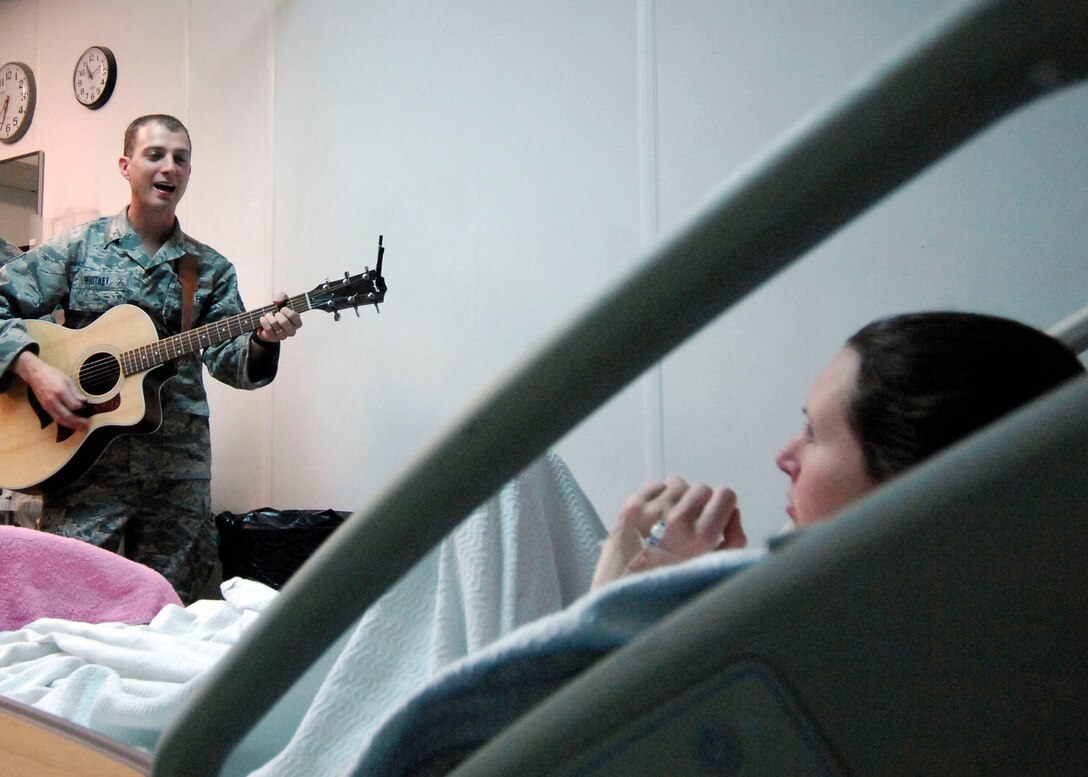 BAGRAM AIRFIELD, Afghanistan -- Staff Sgt. Clint Whitney plays the guitar and sings to Chief Warrant Officer 2 Jennifer Pero here, Sept. 30, 2009, at the Craig Joint Theater Hospital.  Sergeant Whitney is deployed from Offutt Air Force Base, Neb., and is a member of FALCON, a U.S. Air Forces Central Command band.  FALCON decided to raise the morale of the hospital patients by singing to them here. "It's really nice to have someone visit; and even better I just got to enjoy the music" said Warrant Officer Jennifer Pero.  Warrant Officer Pero is a Blackhawk pilot deployed from Fort Campbell, Ky., and hails from New London, Conn.  Sergeant Whitney hails from Aberdeen, S.D.   (U.S. Air Force photo/Senior Airman Felicia Juenke)