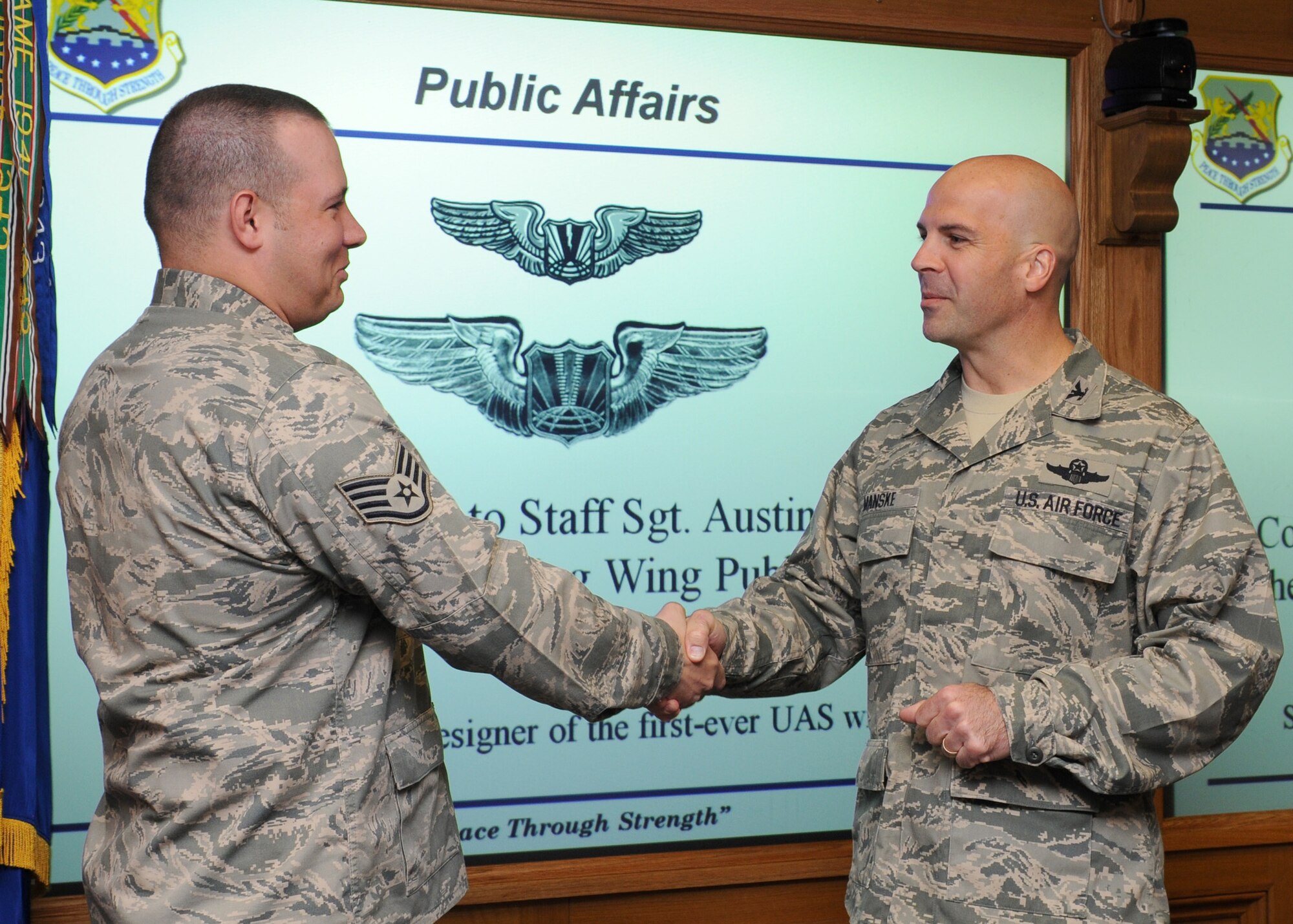 RAF MILDENHALL, England – Staff Sgt. Austin May, 100th Public Affairs internal information NCO in charge, is recognized by Col. Chad Manske, 100th Air Refueling Wing commander, for his design of the unmanned aerial system aeronautical badge that was selected by the chief of staff Gen. Norman Schwartz Sept. 30. The wings were unveiled Sept. 25 with the first graduating class wearing the newly designed wings. (U.S. Air Force/ Staff Sgt. Jerry Fleshman)