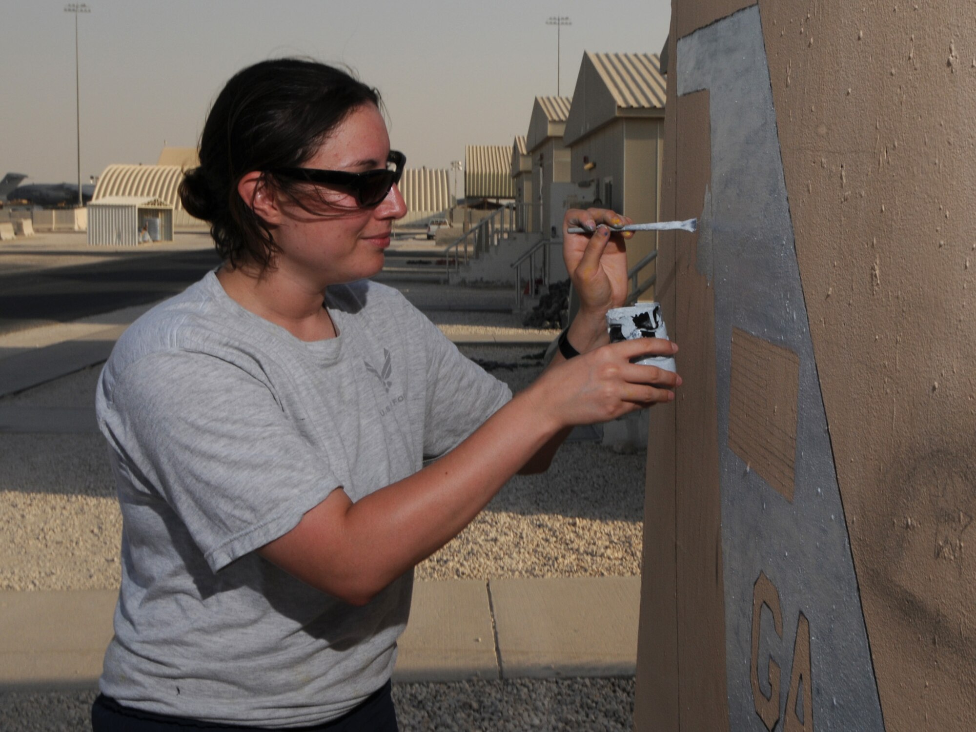 Senior Airman Andrea "Izzy" Iseri-Baker, 7th Expeditionary Air Combat and Control Squadron, paints the unit's jersey barrier. The 7 EACCS is responsible for the JSTARS, an airborne battle management, command and control, intelligence, surveillance and reconnaissance platform. Airman Iseri-Baker is deployed from Robins Air Force Base, Ga., in support of Operations Iraqi and Enduring Freedom. (U.S. Air Force Photo/Tech. Sgt. Jason W. Edwards)