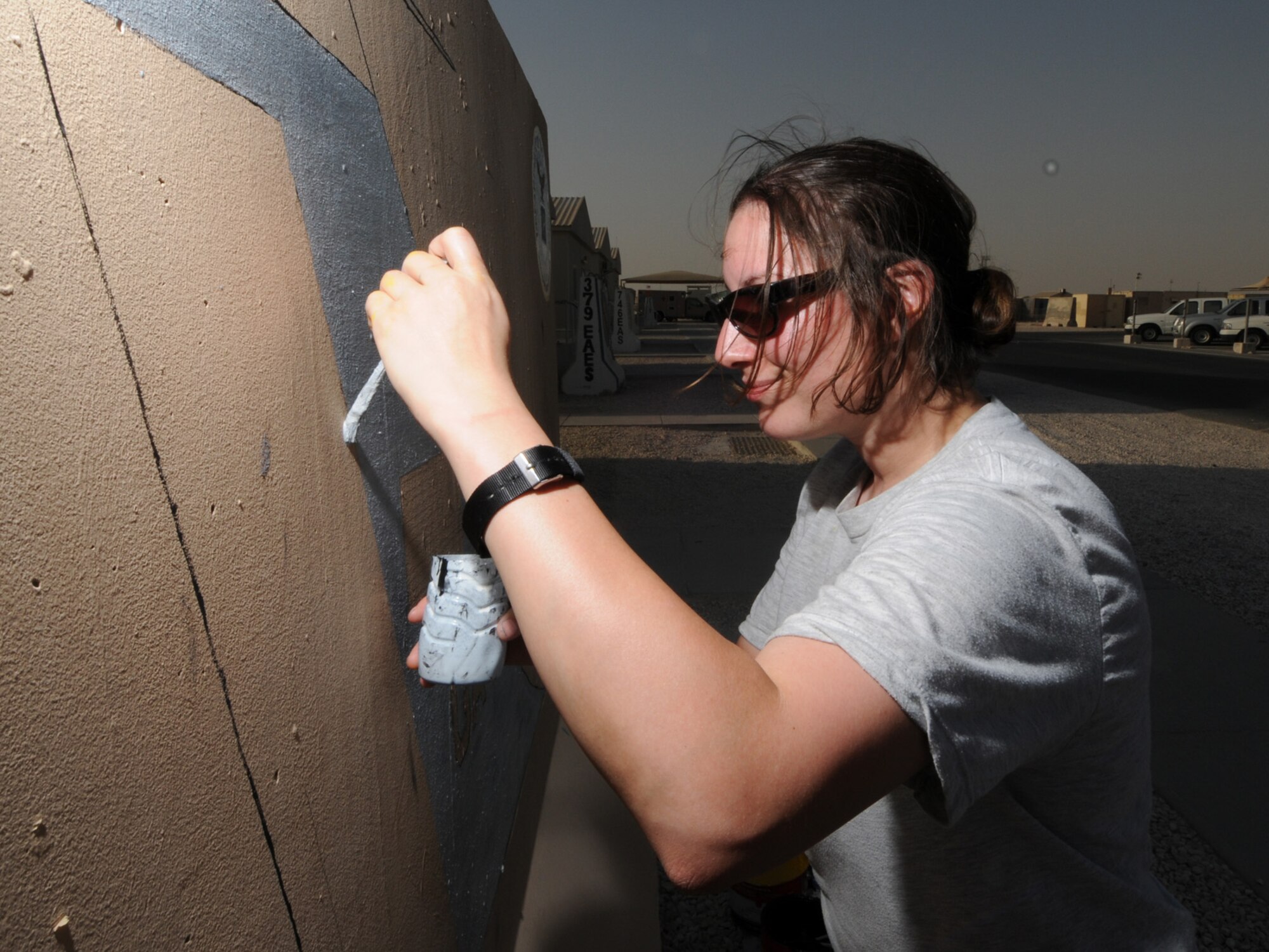 Senior Airman Andrea "Izzy" Iseri-Baker, 7th Expeditionary Air Combat and Control Squadron, paints the unit's jersey barrier. The 7 EACCS is responsible for the JSTARS, an airborne battle management, command and control, intelligence, surveillance and reconnaissance platform. Airman Iseri-Baker is deployed from Robins Air Force Base, Ga., in support of Operations Iraqi and Enduring Freedom. (U.S. Air Force Photo/Tech. Sgt. Jason W. Edwards)