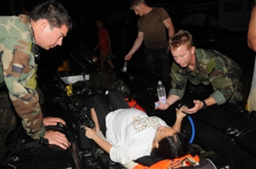 Medical personnel assigned to Joint Special Operations Task Force - Philippines assist a woman in labor during relief efforts in Manila, Philippines, following flooding that destroyed homes and displaced thousands of people in the area on Sept. 27, 2009.  U.S. sailors delivered medical supplies and food and rescued more than 52 people in Manila.  