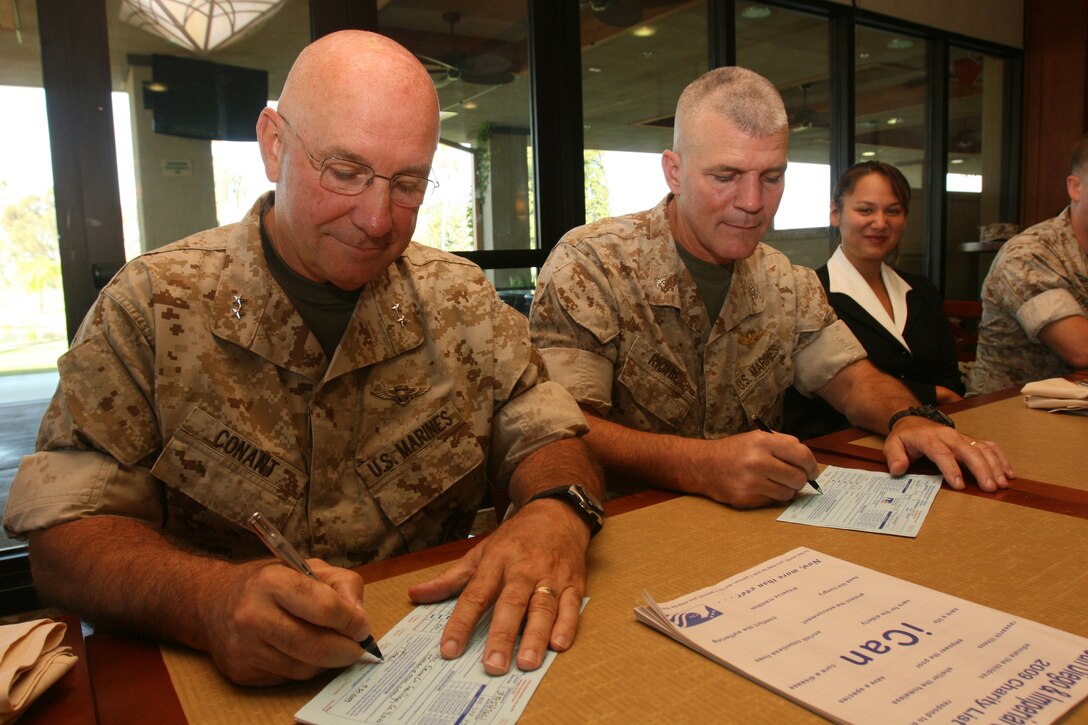 Gen. Thomas L. Conant, the 3rd Marine Aircraft Wing commanding general, and Col. Frank A. Richie, the air station commanding officer, sign their Combined Federal Campaign pledge forms during the air station CFC kick off breakfast at Rockers, Sept. 30. Service members and government employees deployed in other countries participate in the overseas campaigns instead of the CFC.  ::r::::n::(Official U.S. Marine Corps photo by Cpl. Christopher O'Quin)(Released)::r::::n::