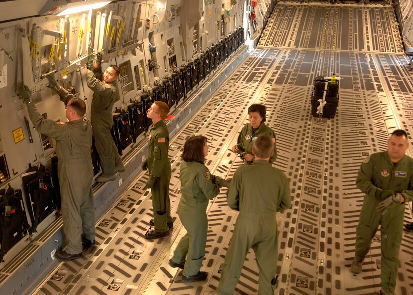 Two U.S. Air Force Members on the left, take down part of a litter station inside a C-17 Globemaster III aircraft as part of the egress training received during the Dissimilar Aircraft Readiness Training Exercise at March ARB, Calif. Dissimilar Aircraft Readiness Training, also known as DART, is a quarterly exercise for Air Force Reserve Command aeromedical evacuation squadrons. It provides hands-on training to flight nurses and aeromedical technicians on different aircraft than they have at their home bases. (U.S. Air Force photo/Senior Airman Joseph Araiza)
