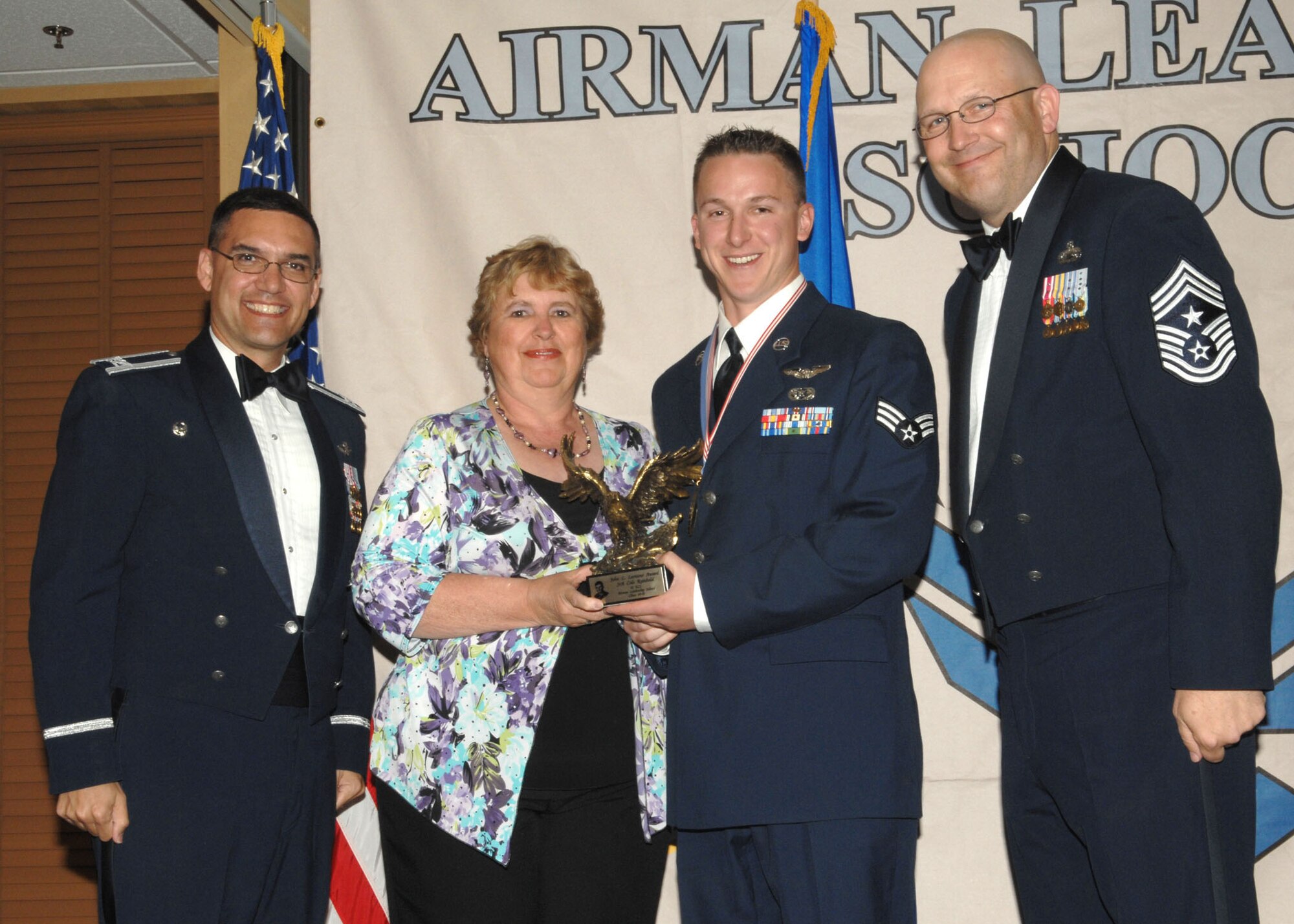 Senior Airman Cole Reinbold (center) of the 42nd Electronic Combat Squadron poses with Mrs. Shirly Wilka of the Military Affairs Committee, 55th Electronic Combat Group Commander Col. Dean Worley (left), and 355th Fighter Wing Command Chief Master Sgt. Tom Schwenk, after being named the John L. Levitow award winner at the Airmen Leadership School graduation ceremony March 25 at the Mirage Club. Forty-seven enlisted members graduated from Davis-Monthan's ALS, which prepares senior airmen for supervisory duties and foster a commitment to the profession of arms. The John L. Levitow award, the highest honor awarded during enlisted professional military education, is presented to the student who is most outstanding in performance evaluations, demonstrated leadership, and teamwork. (U.S. Air Force photo/Airmen Jerilyn Quintanilla)