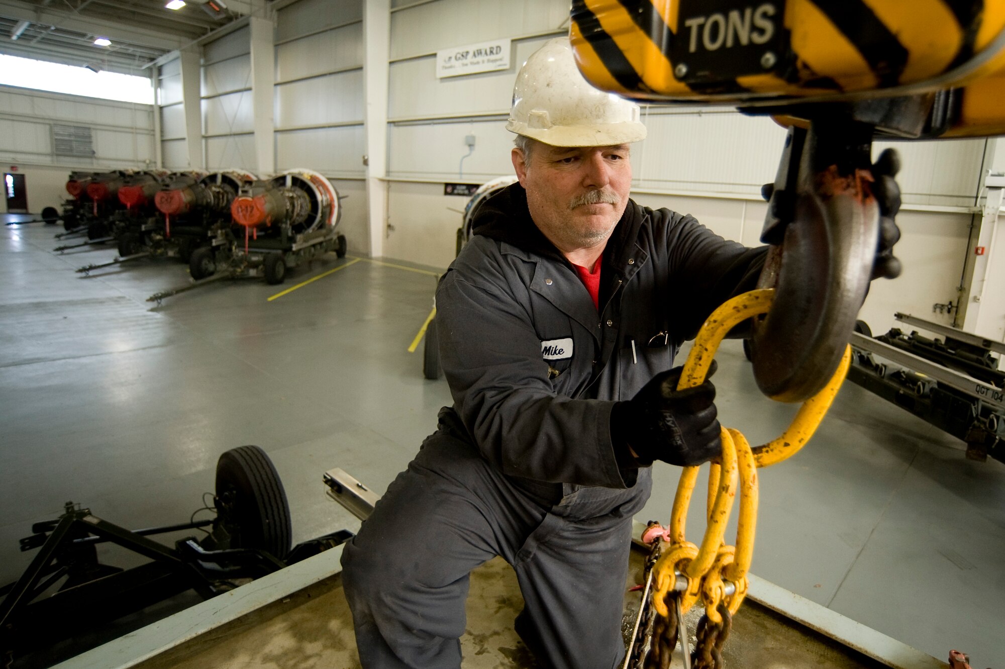 Michael Pittman connects a 14,000 lb. weight to a hoist in preparation to stress test a transport trailer at McChord Field's Module Replacement Center March 31. (U.S. Air Force Photo by Abner Guzman)

