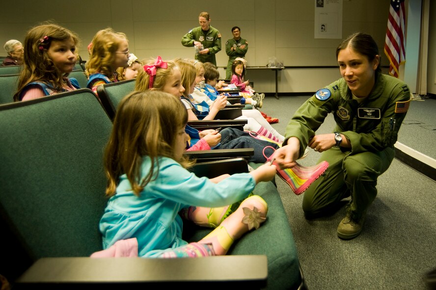 Capt. Jess Lopez, 8th Airlift Squadron, passes out squadron key chains to a group of Girl Scout Daisies and their siblings during an orientation at the squadron auditorium Tuesday, making them honorary members of the squadron for their efforts in support of Operation Cookie Drop. The "Magnolia Daisies" met female pilots and loadmasters from the 8th AS and toured a C-17 Globemaster III static display and simulator as part of their visit to the squadron. (U.S. Air Force Photo by Abner Guzman)