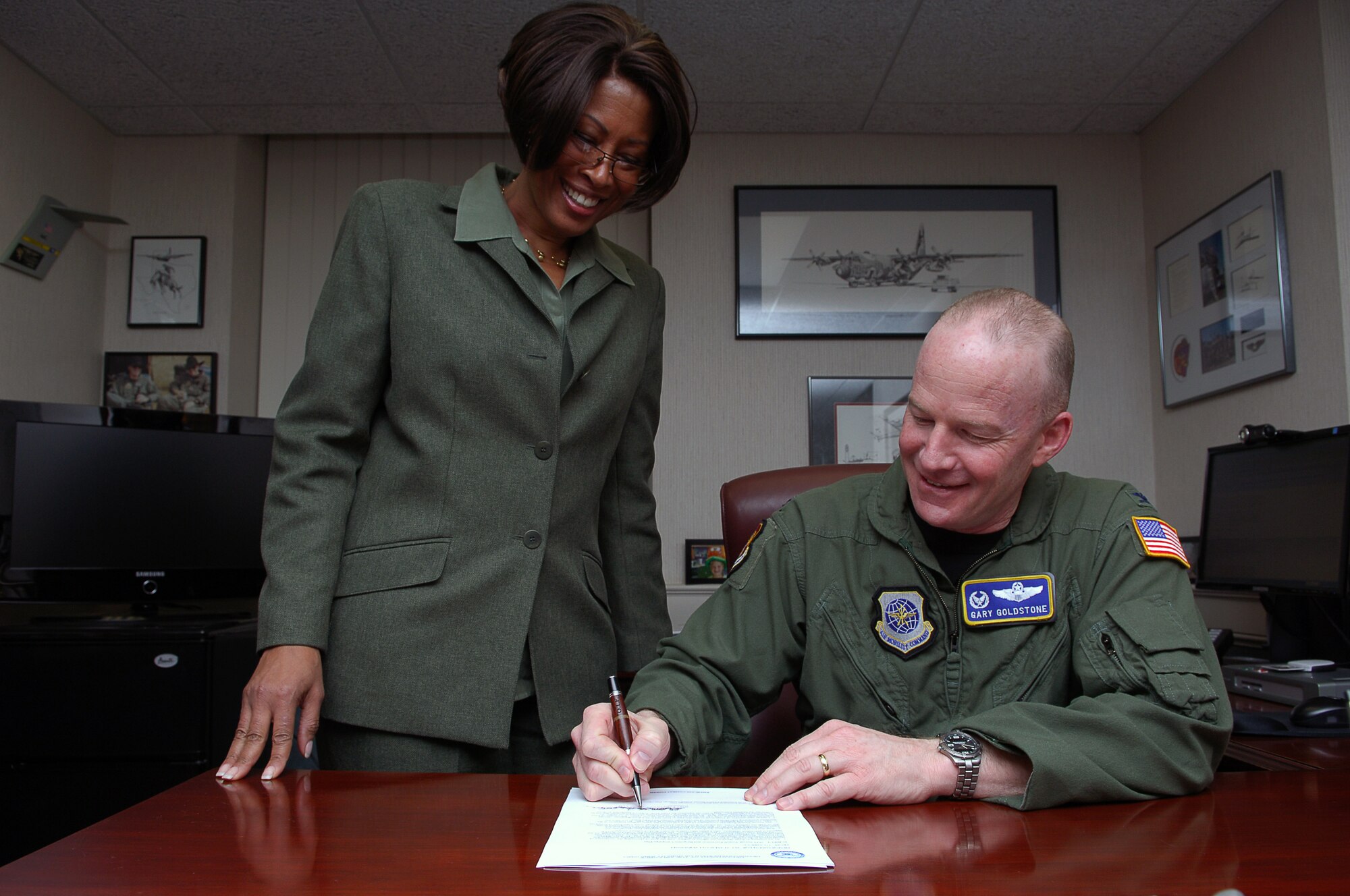 SCOTT AIR FORCE BASE, Ill. -- Col. Gary Goldstone, 375th Air Mobility Wing commander, signs the Scott AFB Sexual Assault Prevention and Response Campaign Plan on March 24 as Ms. Pamela Dorsey, Sexual Assault Response Coordinator, looks on. (U.S. Air Force photo/Senior Airman Ryan Crane)