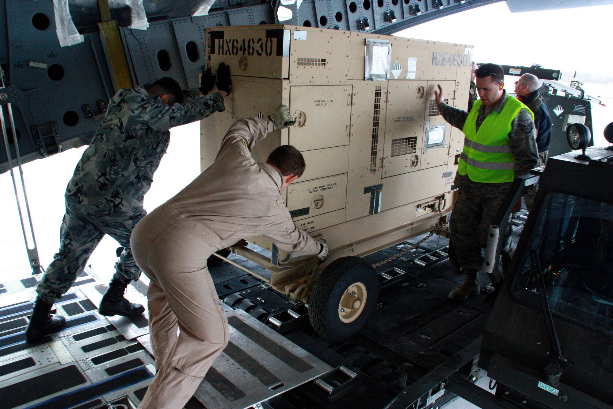 Airmen from the multinational Heavy Airlift Wing move equipment in preparation for shipment to units in Afghanistan, March 30. The HAW moved more than 2.1 million pounds of War Reserve Material essential to surge operations supporting the International Security Assistance Force in Afghanistan. The HAW, based at Pápa Air Base, Hungary, operates three C-17 Globemaster III aircraft independently of NATO's military command and is comprised of 12 nations that activated the unit, July 27, 2009. (Photo by Finnish Capt. Juha Miettinen, HAW)