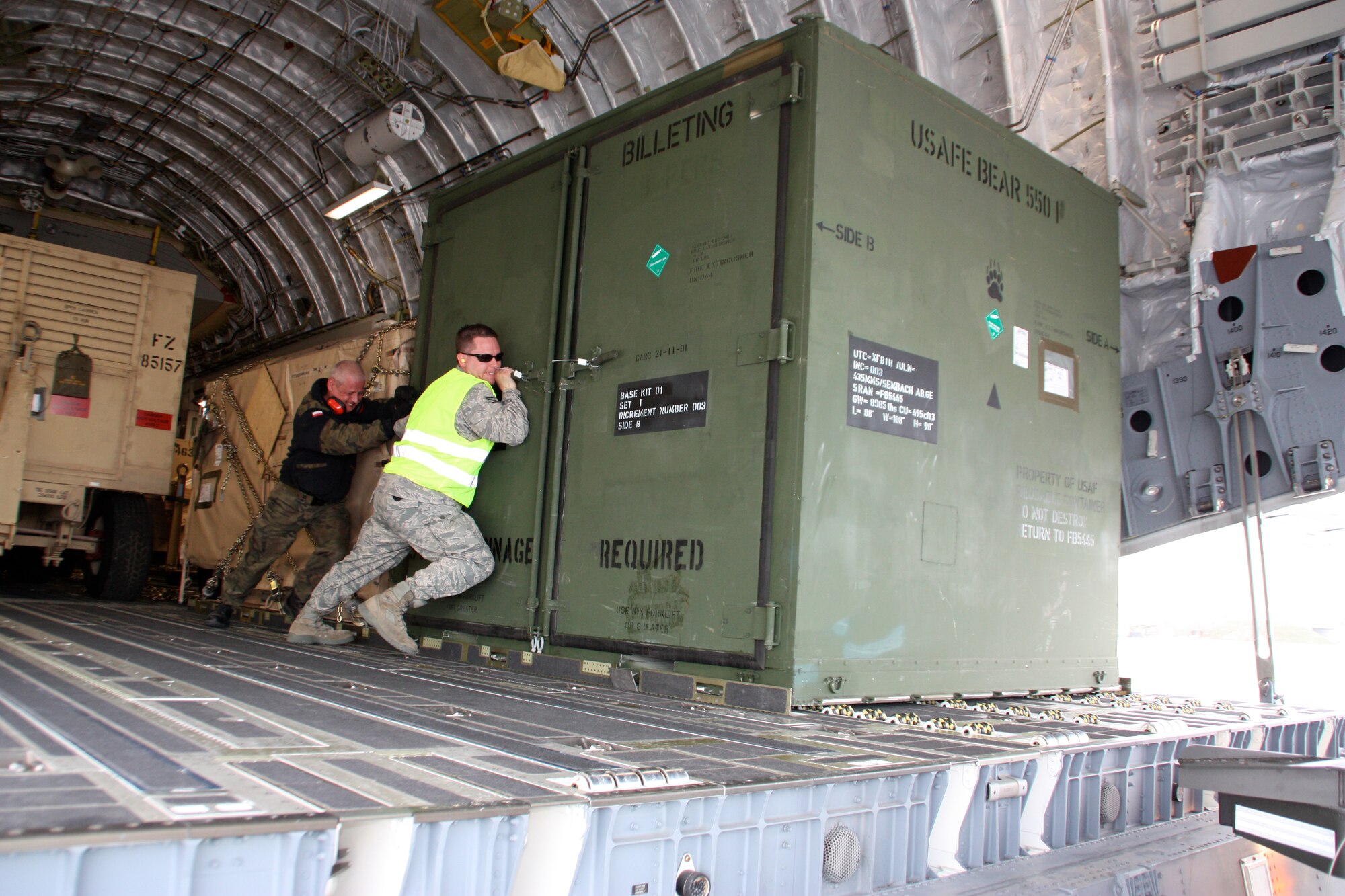 Airmen from the multinational Heavy Airlift Wing move a billeting BEAR (basic expeditionary airfield resources) kit in preparation for shipment to units in Afghanistan, March 30. The HAW moved more than 2.1 million pounds of War Reserve Material essential to surge operations supporting the International Security Assistance Force in Afghanistan. The HAW, based at Pápa Air Base, Hungary, operates three C-17 Globemaster III aircraft independently of NATO's military command and is comprised of 12 nations that activated the unit, July 27, 2009. (Photo by Finnish Capt. Juha Miettinen, HAW)