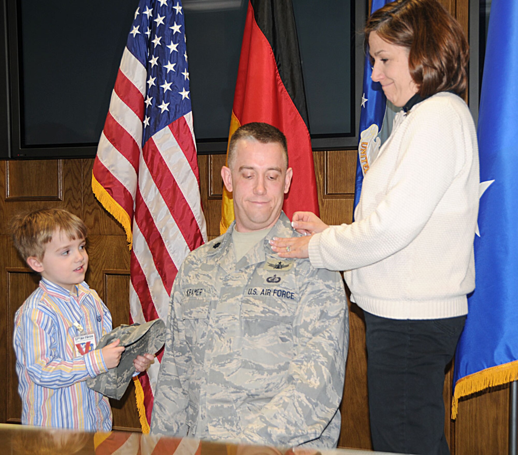 Lt. Col. Thomas Kramer receives assistance from his son Eli and wife Angela, in pinning on his new rank to lieutenant colonel during his promotion ceremony Mar. 31. Colonel Kramer is the 17th Air Force Chief of Global Force Management in the Operations Directorate (A3). (U.S. Air Force photo by Staff Sgt. Stefanie Torres)