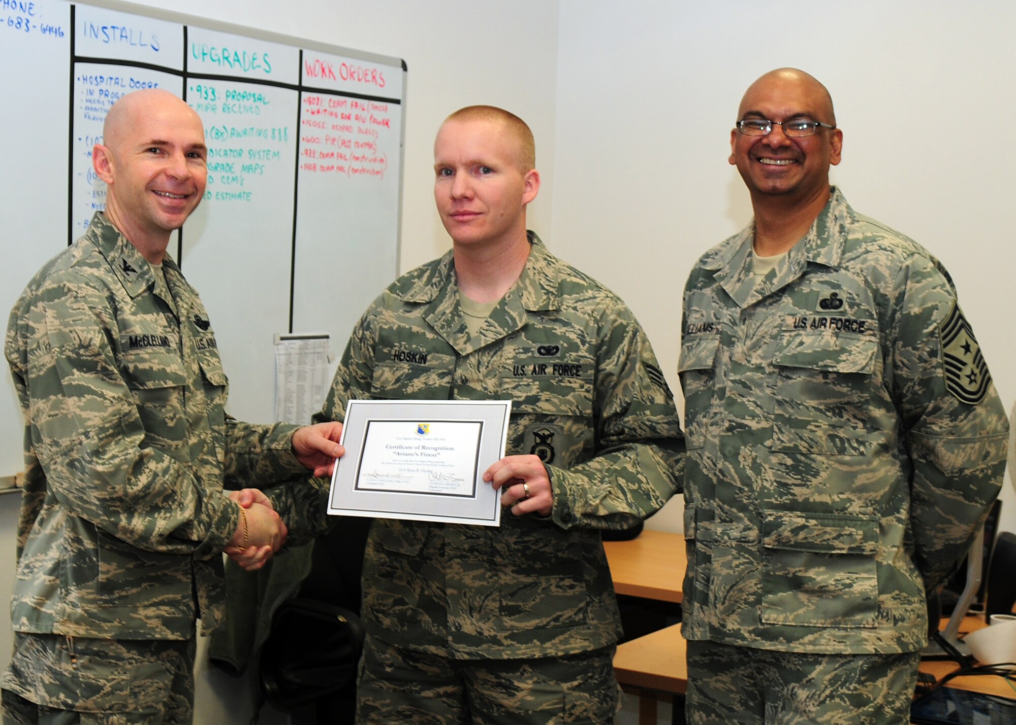 Col. Patrick A. McClelland, 31st Fighter Wing vice commander, congratulates Senior Airman Ryan Hoskins, 31st Security Forces Squadron electronic systems security non-commissioned officer in charge, on his selection as one of Aviano's Finest as Chief Master Sgt. Laten Williams, 31st FW command chief, looks on. (U.S. Air Force photo/ Senior Airman Taylor Marr)
