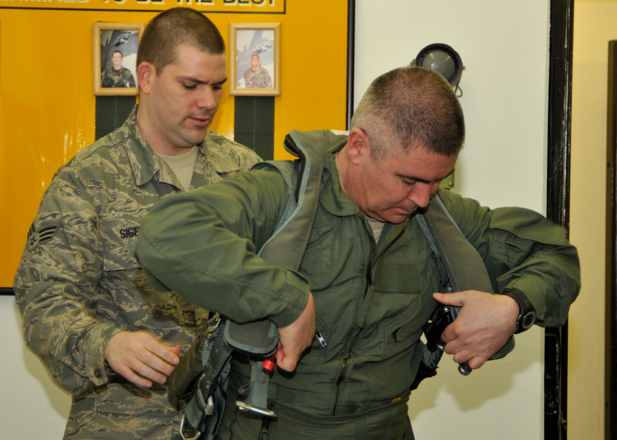 Senior Airman David Sigers, 48th Operational Support Squadron Aircrew Flight Equipment journeyman, assists Chief Master Sgt. James Lucas, 48th Fighter Wing command chief, with his flight suit at the 493rd Fighter Squadron on March 26 in preparation for his incentive flight. (U.S. Air Force photo/Airman 1st Class Tiffany Deuel)