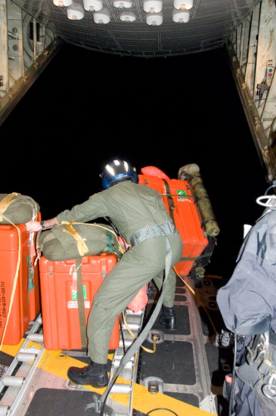 Petty Officer 2nd Class Dan Booth, a drop master from Air Station Sacramento, pushes watertight drop boxes containing rescue equipment out the rear door of a C-130 Hercules airplane approximately 1,400 miles southwest of San Diego April 1, 2010.The Coast Guard and Air National Guard worked together to respond to medevac an injured 57-year-old man by dropping four pararescuemen, an inflatable boat and other rescue and survival equipment. (U.S. Coast Guard photo by Petty Officer 3rd Class Henry G. Dunphy)