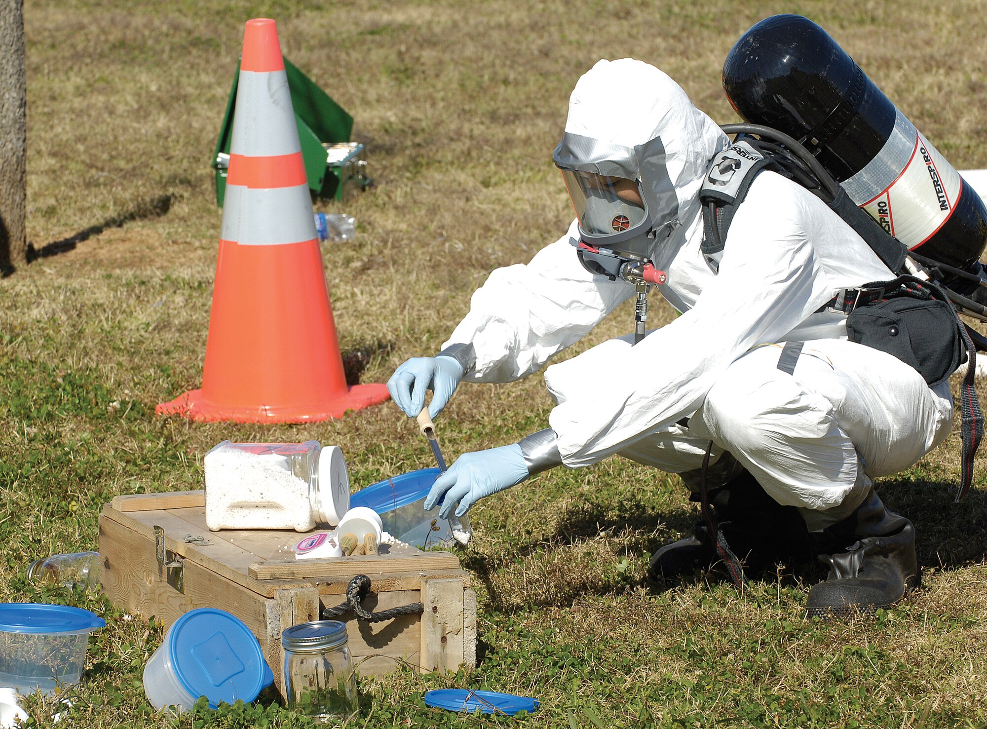 Bioenvironmental Engineering Flight personnel are called when the identity and threat level of an unknown substance needs to be identified during emergencies. While a wide protective area is secured around an exercise scene, as in a real life emergency, samples of the suspicious substance are gathered for testing by flight personnel in protective gear. (Air Force photo by Margo Wright)