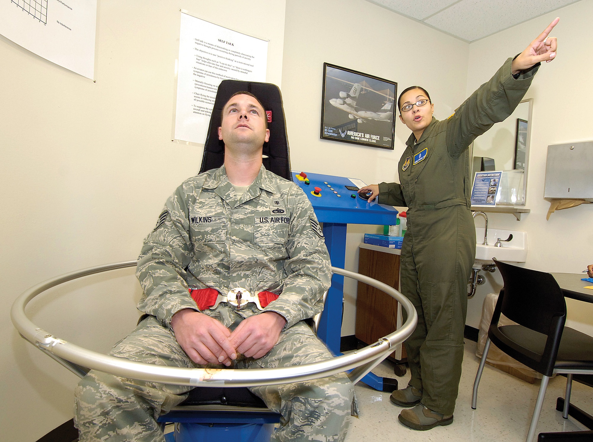 Teaching flight crew members how to handle airsickness is a responsibility of Flight Medicine.  A Barany chair spins a crew member poised in various positions to simulate motions during flight.  Staff Sgt. Isabel Brooks, the NCOIC of Human Performance, instructs the person to focus on a fixed point during a spin in the chair.  Overcoming motion sickness is vital for air crews, teaching them to trust their instruments and not what the human senses tell them. (Air Force photo by Margo Wright)