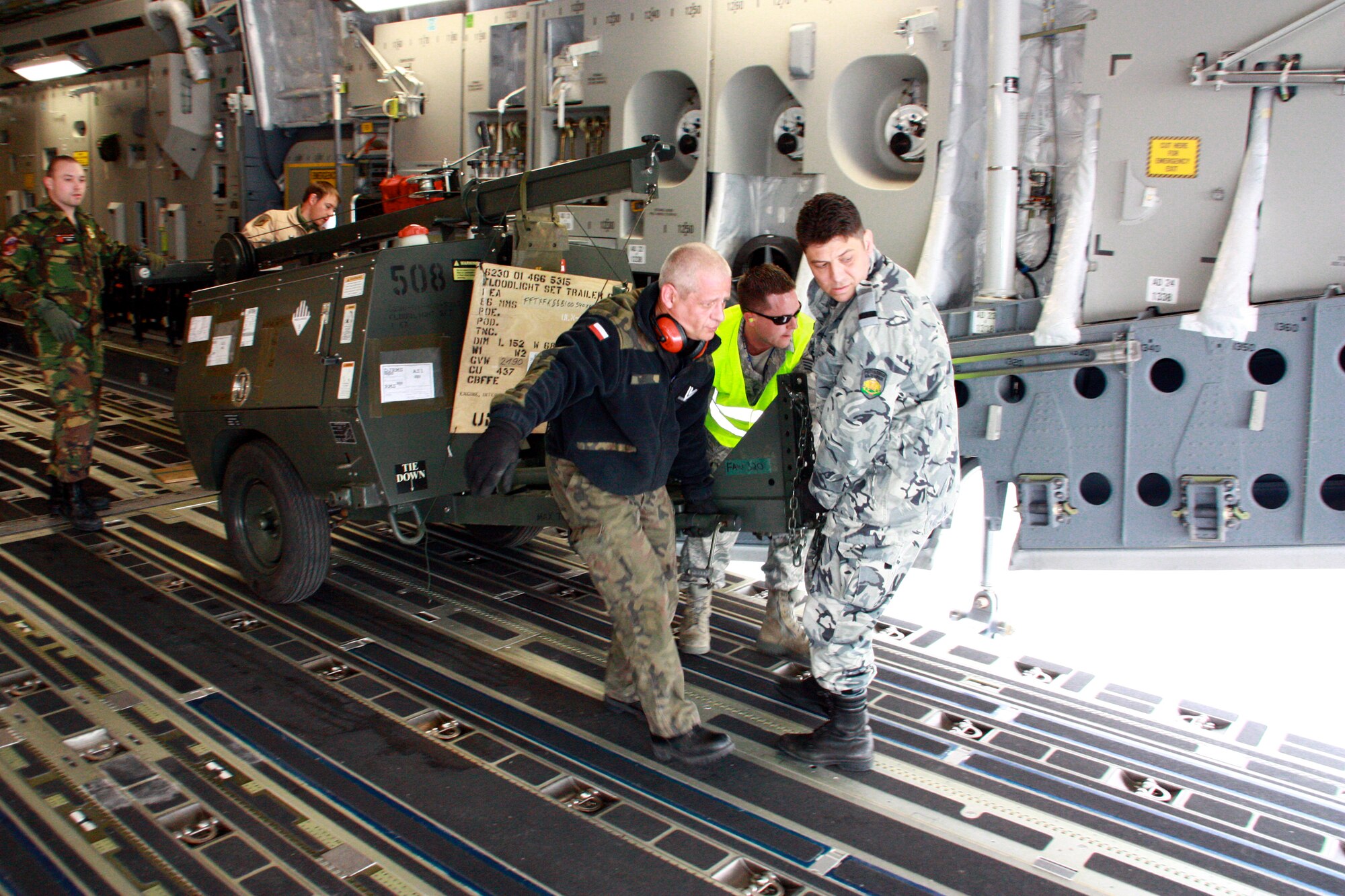 Airmen from the multinational Heavy Airlift Wing move a floodlight set trailer March 30, 2010,  in preparation for shipment to units in Afghanistan. HAW Airmen have moved more than 2.1 million pounds of war reserve material essential to surge operations supporting the International Security Assistance Force in Afghanistan. The HAW, based at Papa Air Base, Hungary, operates three C-17 Globemaster III aircraft independently of NATO's military command and comprises 12 nations that activated the unit July 27, 2009. (HAW photo/Finnish Capt. Juha Miettinen)