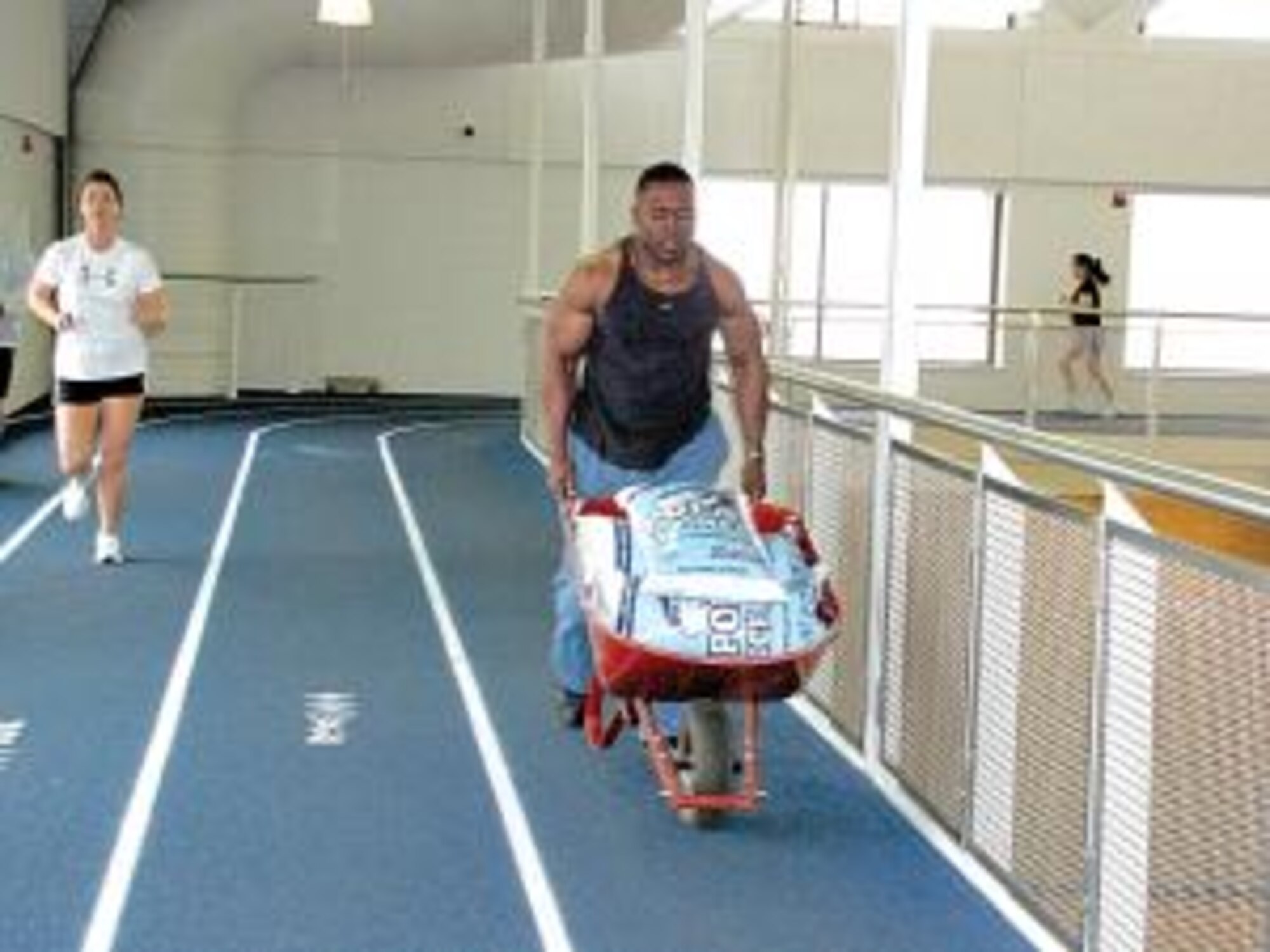 Staff Sgt. Charles Raphiel, of the 4th Aircraft Maintenance Unit, maneuvers a wheelbarrow filled with bags of salt as he completes the last portion of the obstacle that was laid out along the indoor track at the Warrior Health and Fitness Center. (Air Force photo by Lee Anne Hensley)