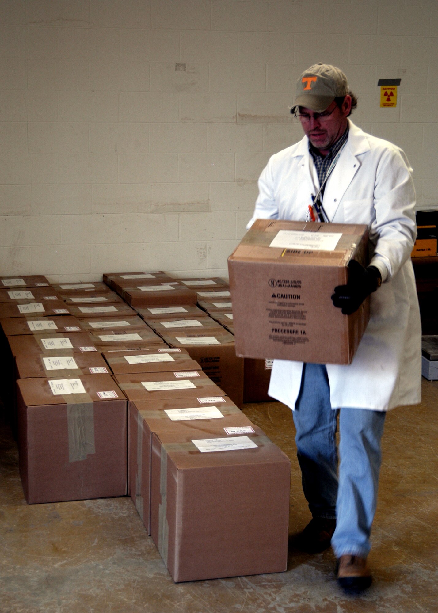 Chris Anthony, Radioactive Material Program Manager, with the Radiation Branch carries a sealed box of old tritium exit signs to load on a truck for shipment to a recycling center in Las Vegas.  (U.S. Air Force by Ted Theopolos)