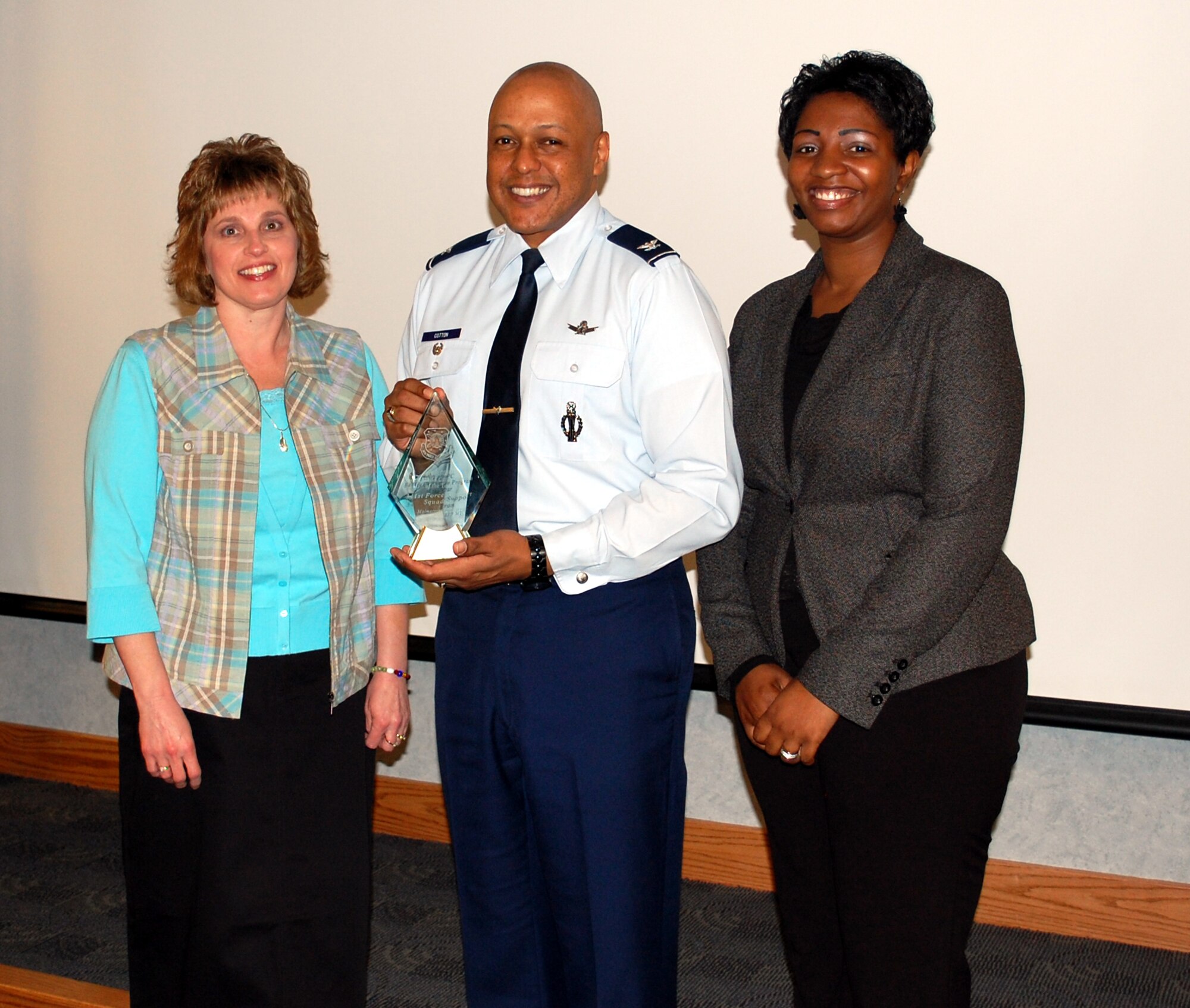 Marjorie Hahn, director; Col. Anthony Cotton, 341st Missile Wing vice commander; and Shatoyia Bradley, office assistant, pose with the Air Force Space Command Family Child Care Program of the Year Award March 22. Some of their accomplishments included a 98 perceont satisfaction rating from parents who used family child care homes, and more than $42K in savings to military families through three child care options sponsored by their programs. (U.S. Air Force photo/2nd Lt. Marshel Slater)