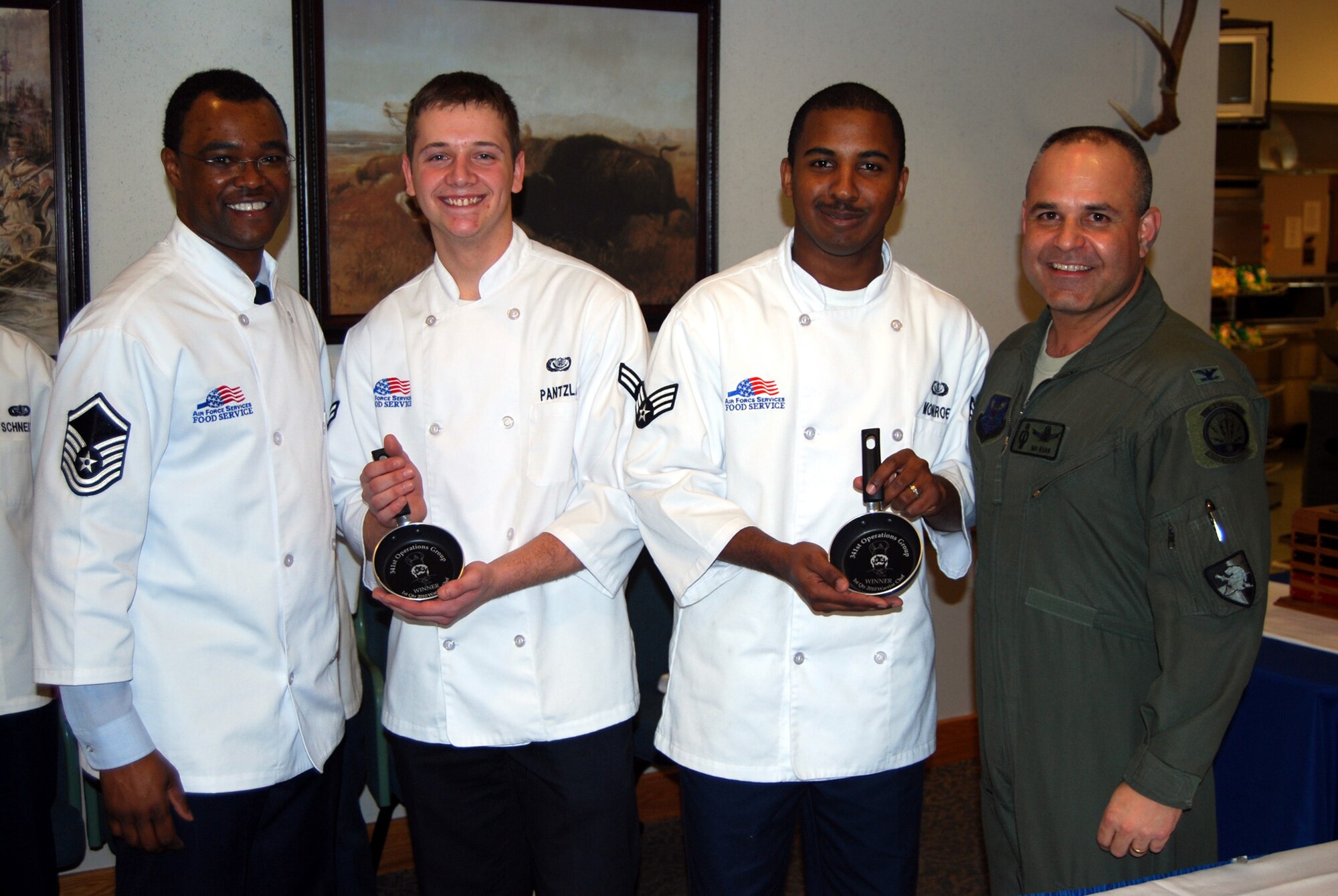 The 10th Missile Squadron team of Airman 1st Class Tyler Pantzlaff and Senior Airman Maurice Monroe display their winning frying pan plaques. Also pictured are Chef Superintendent Master Sgt. Ricky Woods and 341st Operations Group Commander Col. Mo Khan. (U.S Air Force photo/Airman 1st Class Kristina Overton)