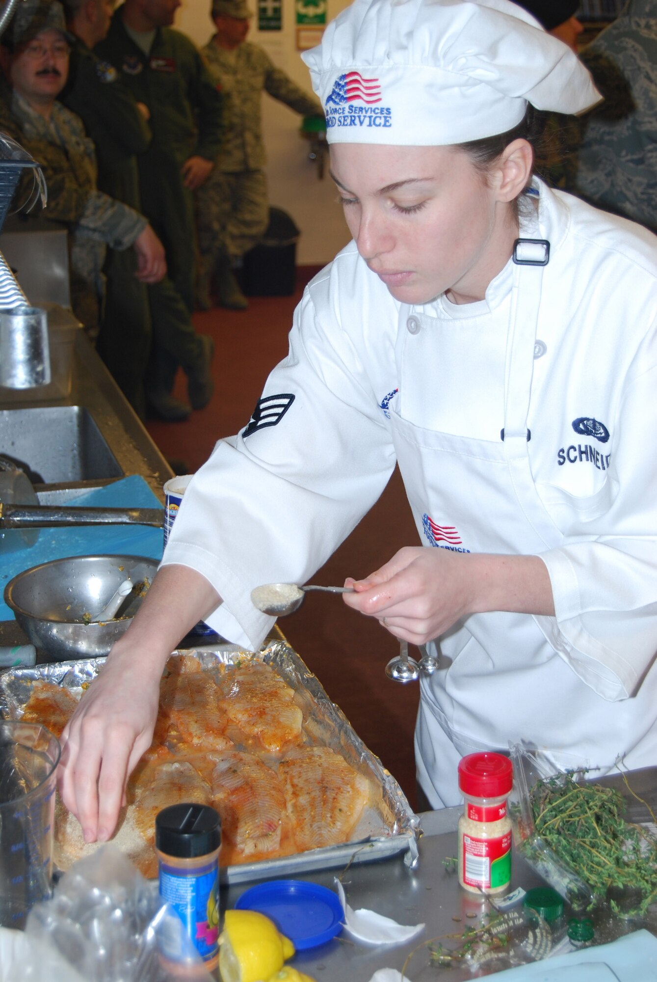 Senior Airman Lindsay Schneider works busily seasoning her catfish fillets with a variety of spices.  She participated in the Warrior Chef competition for the 12th Missile Squadron. (U.S Air Force photo/Airman 1st Class Kristina Overton)
