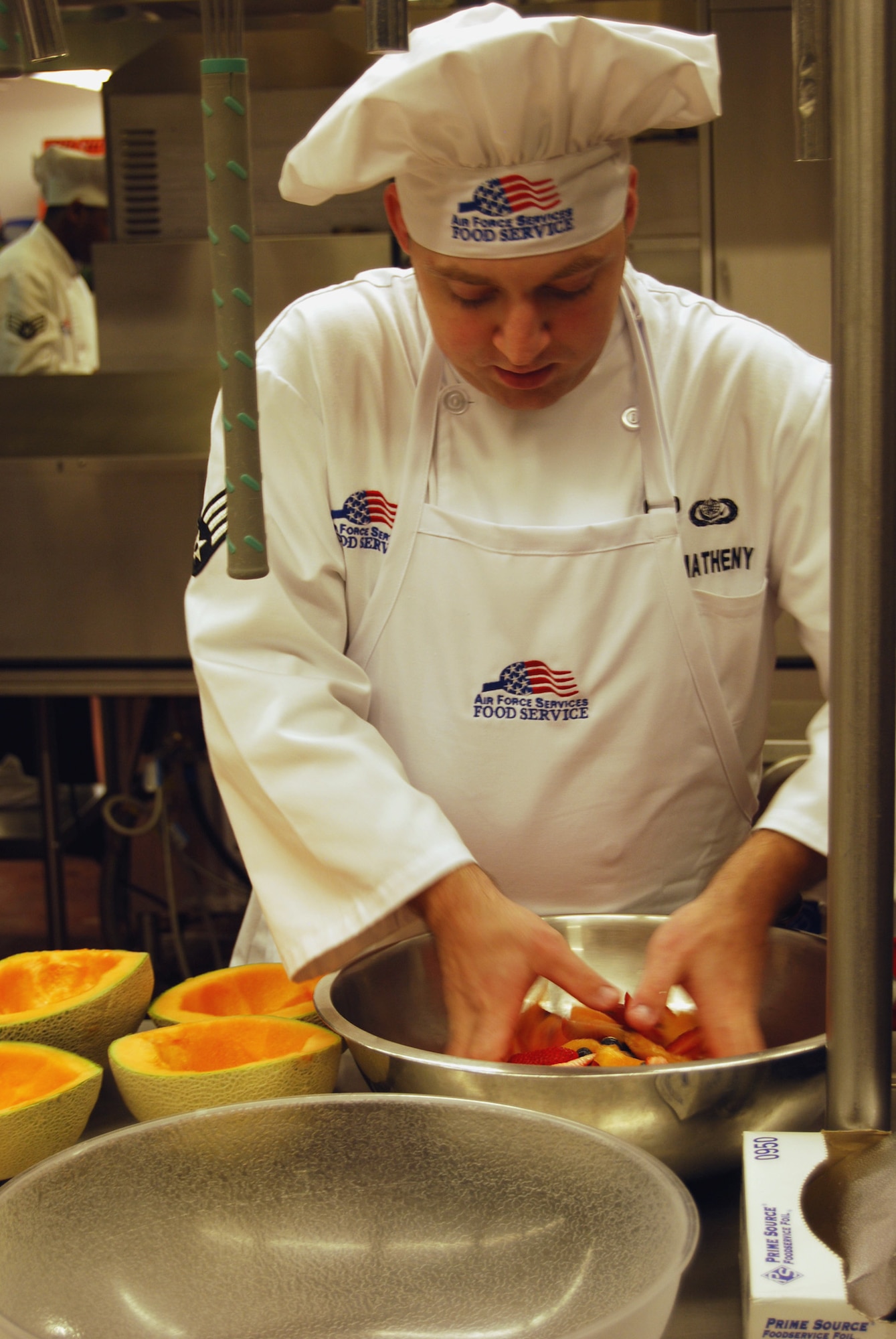 Senior Airman Harold Matheny tosses sliced fresh fruit  before putting it into the cantaloupe dishes for presentation to the judges at the Warrior Chef competition March 22.(U.S Air Force photo/Airman 1st Class Kristina Overton)