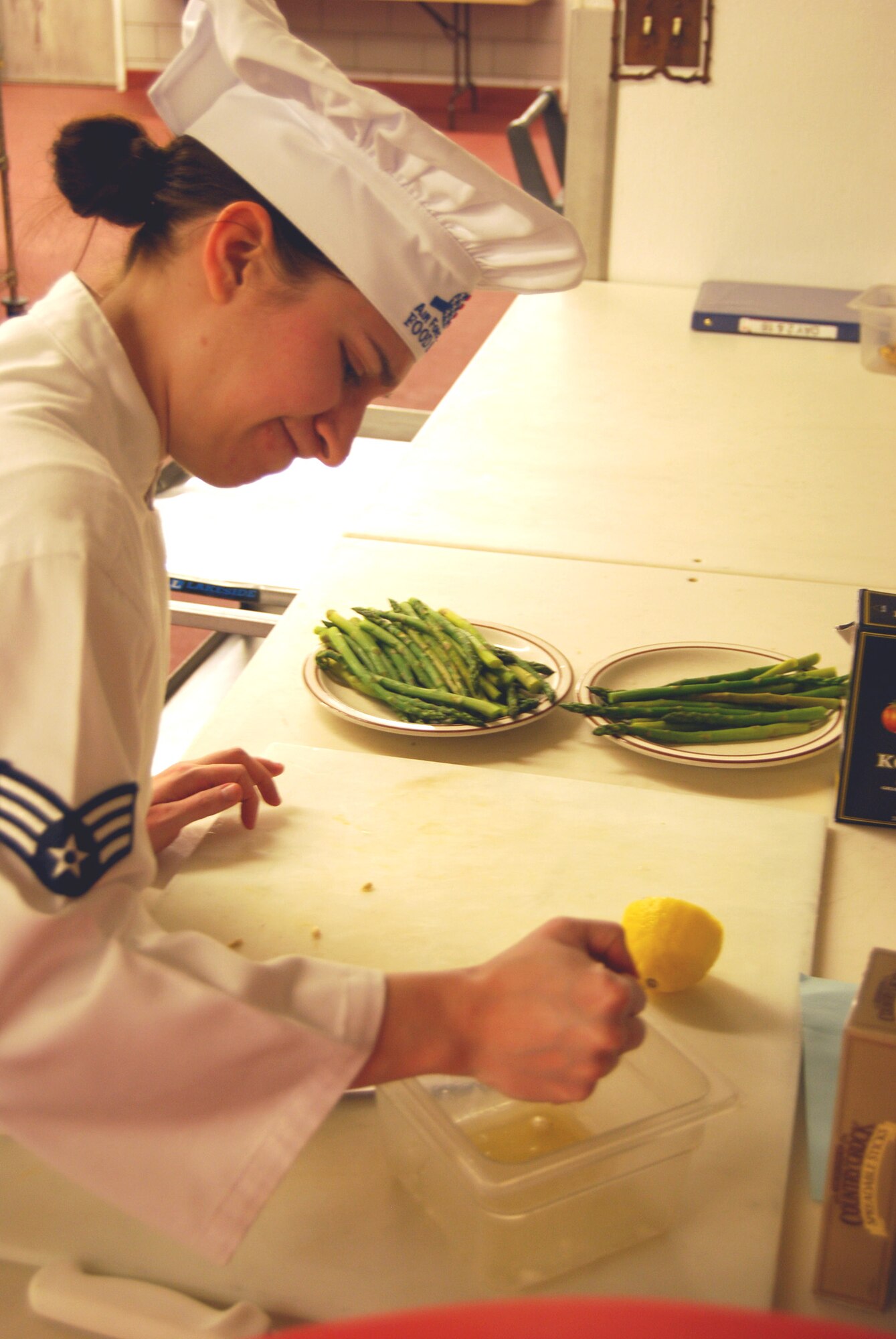 Senior Airman Eleanor Fyler, 12th Missile Squadron chef, uses some muscle to squeeze every last drop out of a fresh lemon, the common ingredient for the Warrior Chef competition.(U.S Air Force photo/Airman 1st Class Kristina Overton)