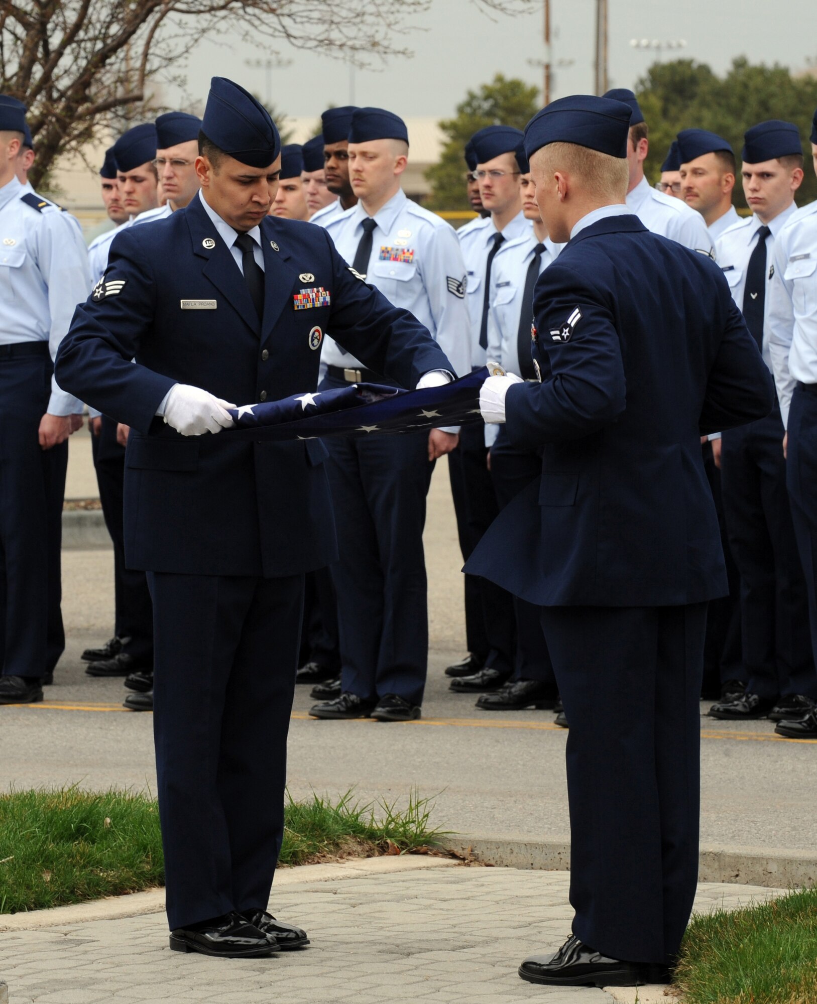 MOUNTAIN HOME AIR FORCE BASE, Idaho -- Senior Airman Sabastian Mafla Proano (left) and Airman 1st Class Kurtis Brown, both from the 366th Civil Engineering Squadron fold the American flag during a retreat ceremony at the 366th Fighter Wing Headquarters March 29. 366th CES hosted the retreat in memory of Tech. Sgt. Walt Moss, 366th CES explosive ordnance disposal apprentice. Sergeant Moss was the first United States Air Force EOD Airman to be killed in combat since the start of Operation Enduring Freedom and Operation Iraqi Freedom, and was killed near Baghdad during safing operations. (U.S. Air Force photo by Airman 1st Class Debbie Lockhart)