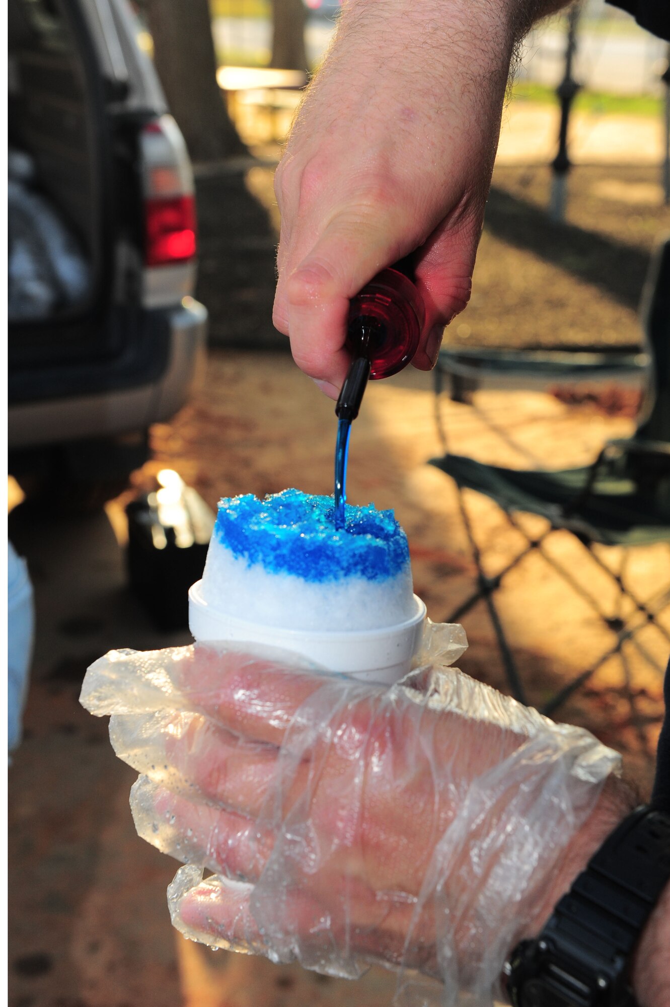 SHAW AIR FORCE BASE, S.C. -- Jesse Voison, Snowie of Sumter operator, pours blue raspberry flavoring over the Sno Ball during the Month of the Military Child Carnival here April 1. (U.S Air Force photo by/Senior Airman David Minor)