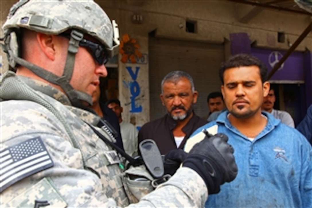 U.S. Army Cpl. Patrick Bramlett (left) from Tactical Psychological Operations Detachment 1070, attached to the 17th Fires Brigade takes notes on key points during discussions with locals in Al Qurnah, Iraq, on Mar. 20, 2010.  Bramlett spoke to local Iraqis about the local economy, the recent elections and security in their neighborhood.  